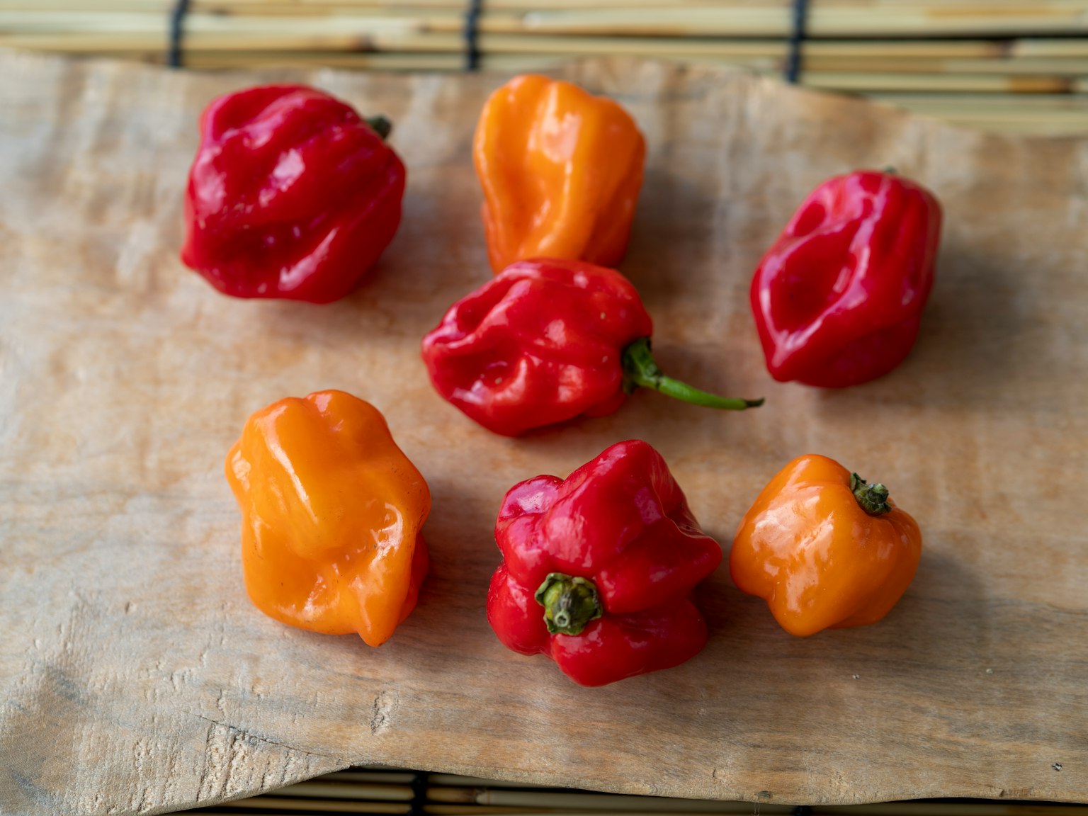 Peperoni habanero rossi e arancioni disposti su una tavola di legno