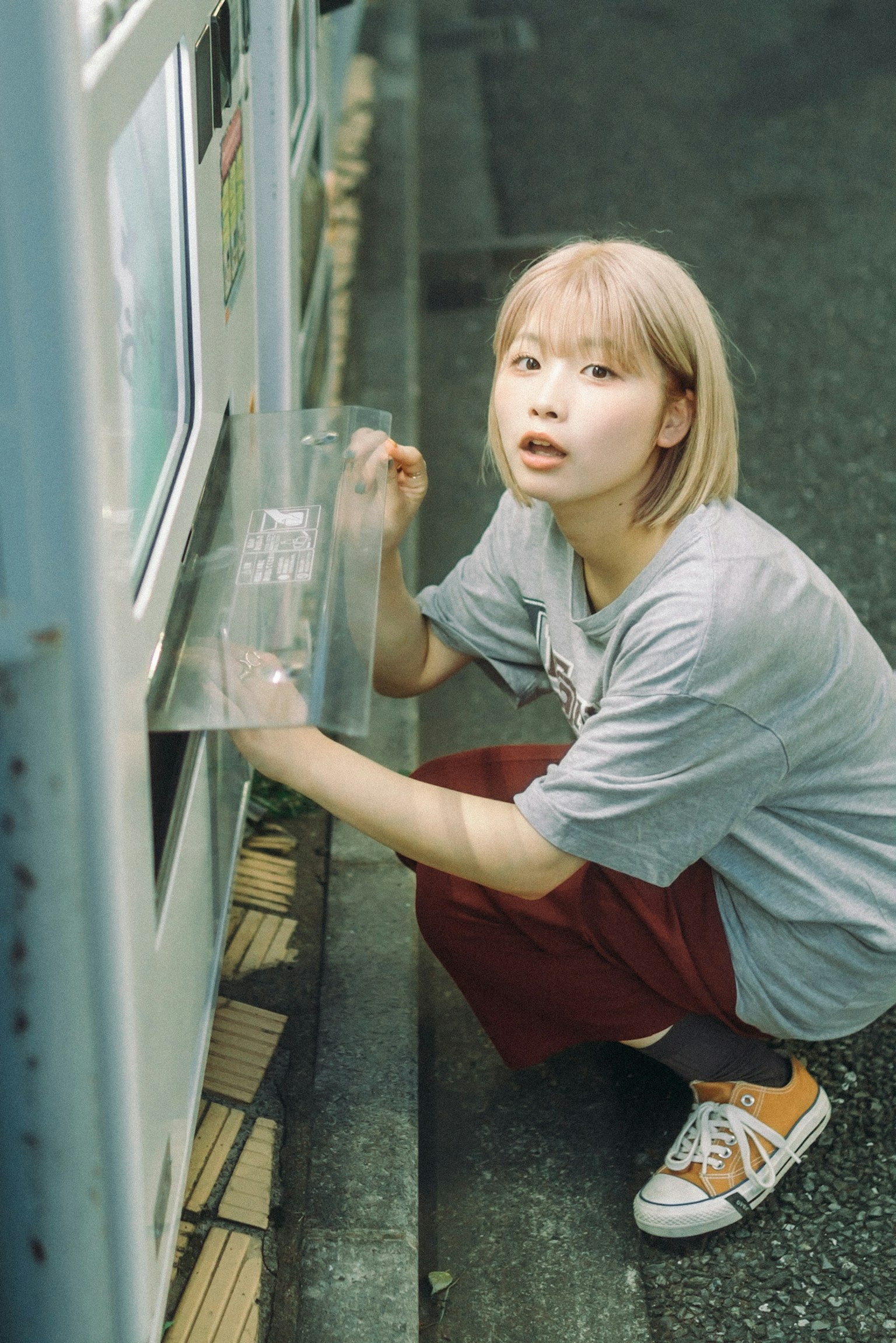 자판기 앞에 쪼그리고 앉아 있는 소녀