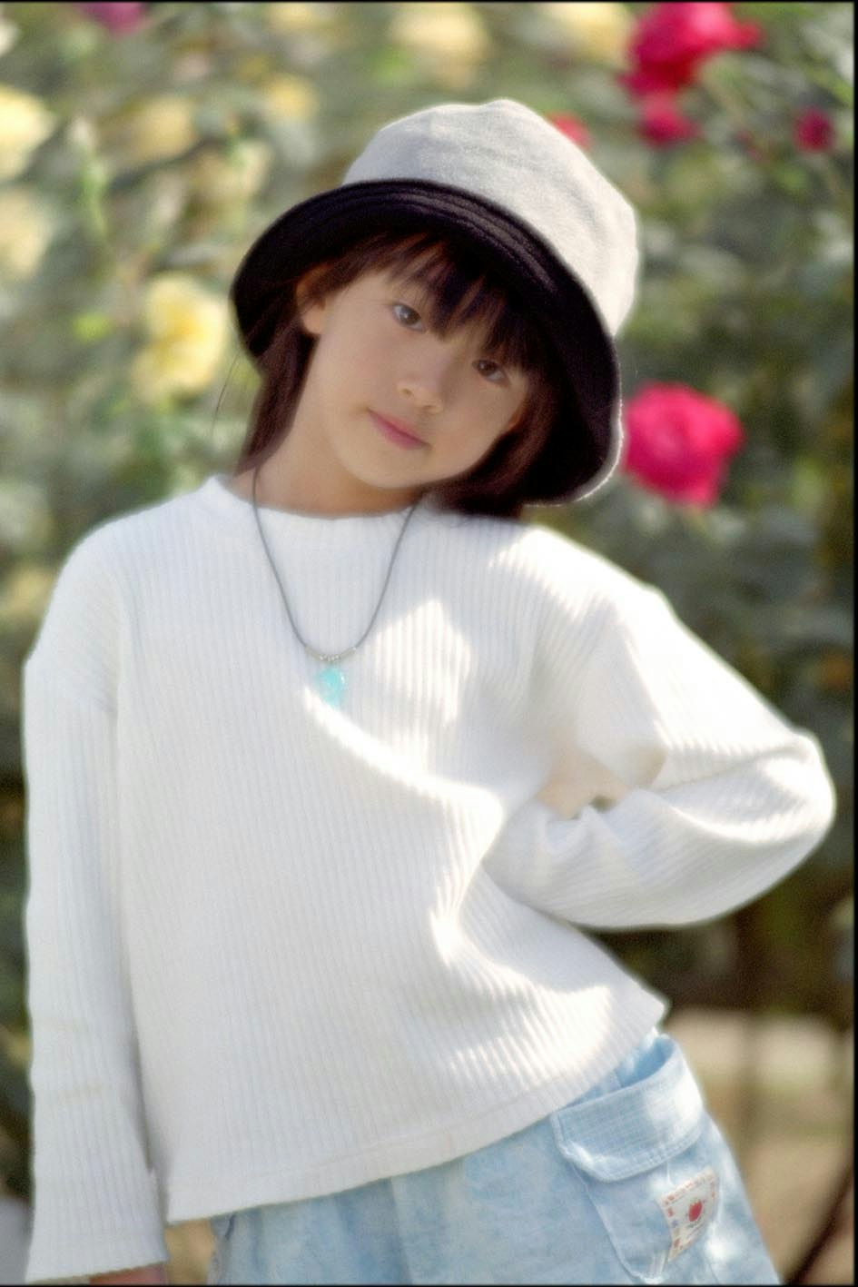 Retrato de una mujer con sombrero frente a un jardín de flores