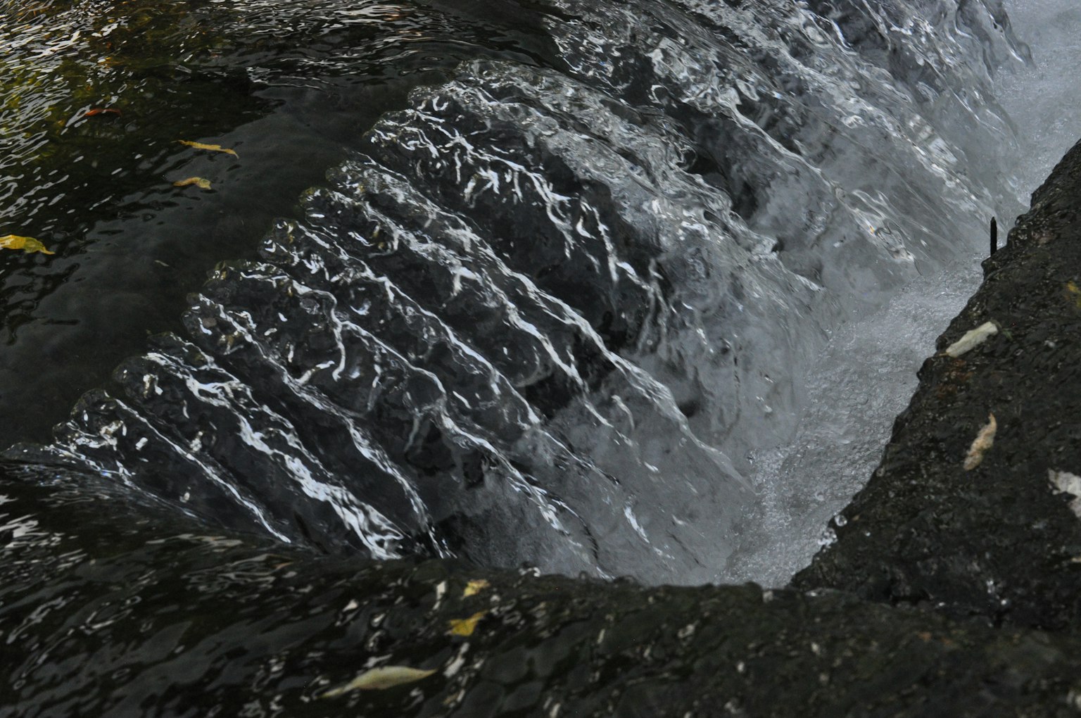 Immagine di una piccola cascata che mostra acqua che scorre e una struttura di pietra