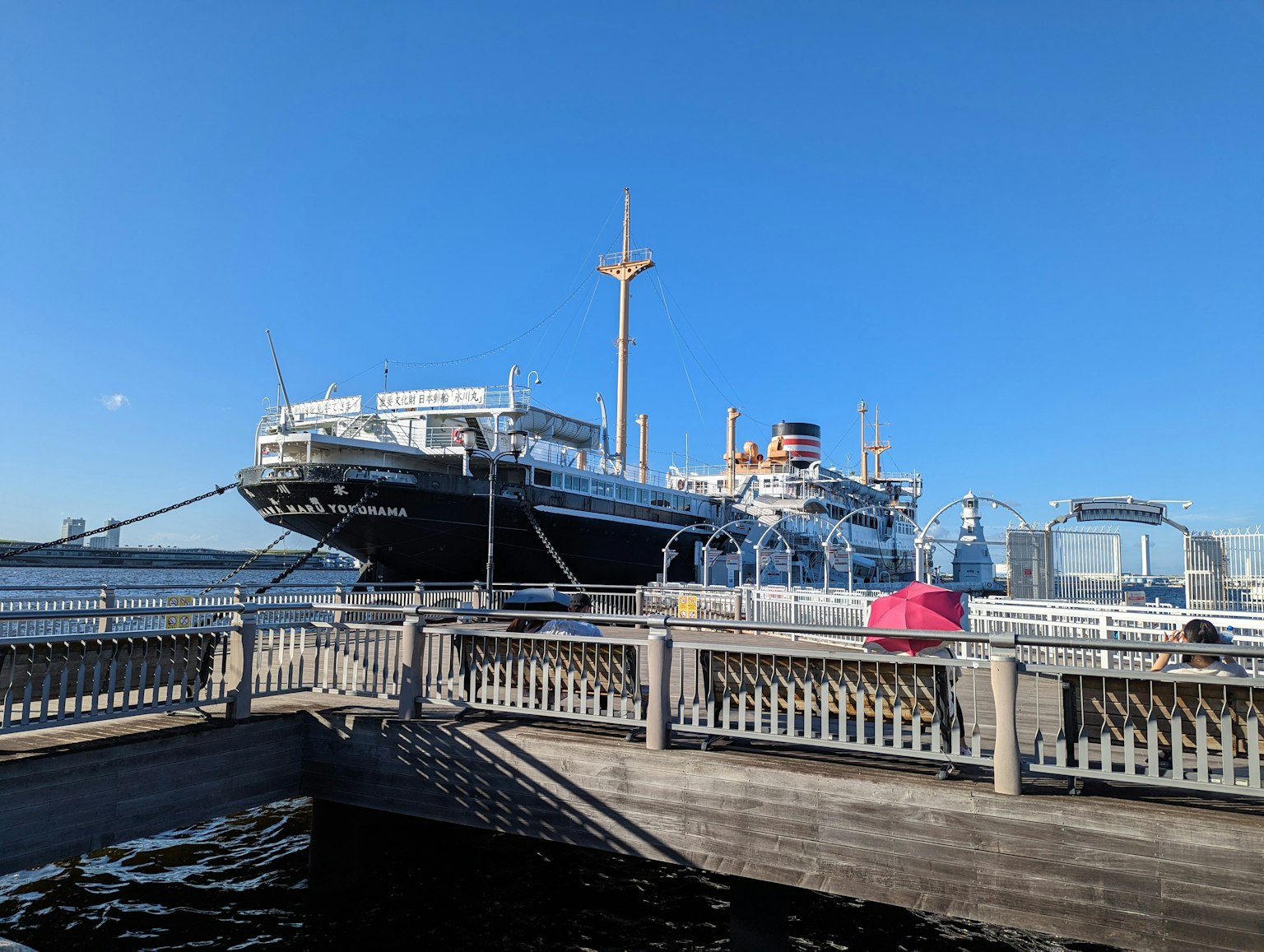 Large ship docked under a clear blue sky with a wooden pier