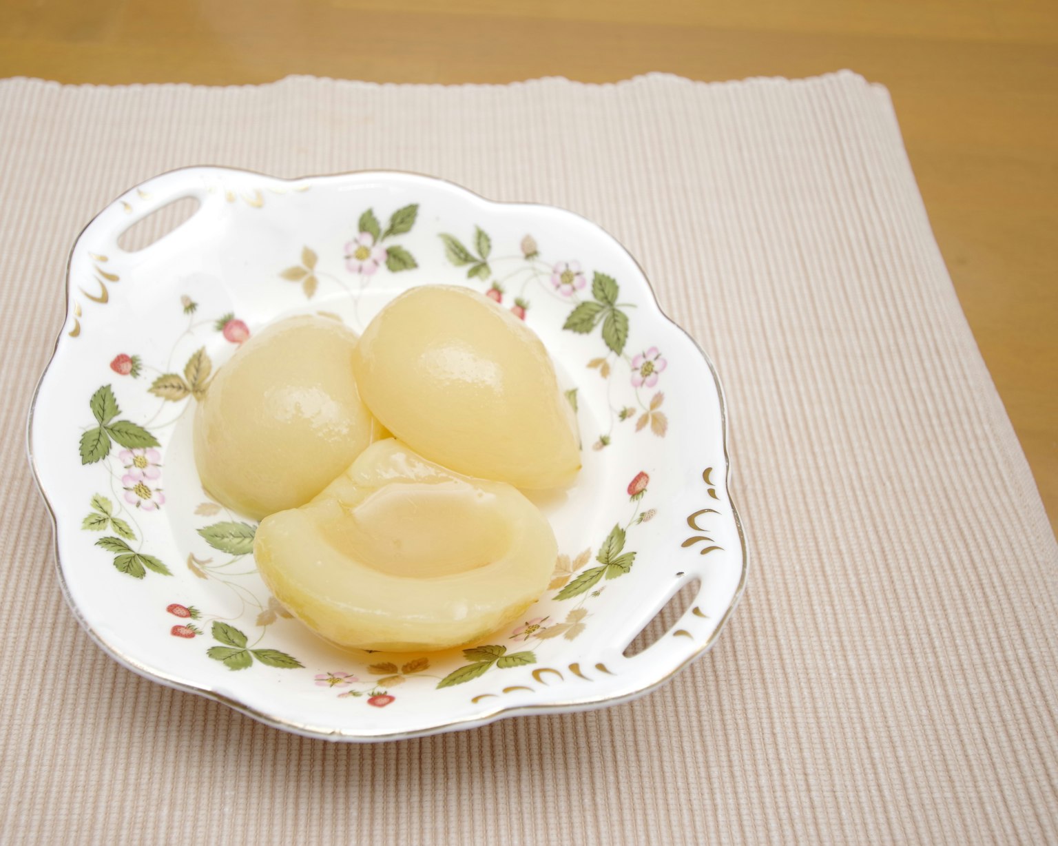 Pesche gialle sciroppate dolci servite su un piatto floreale bianco