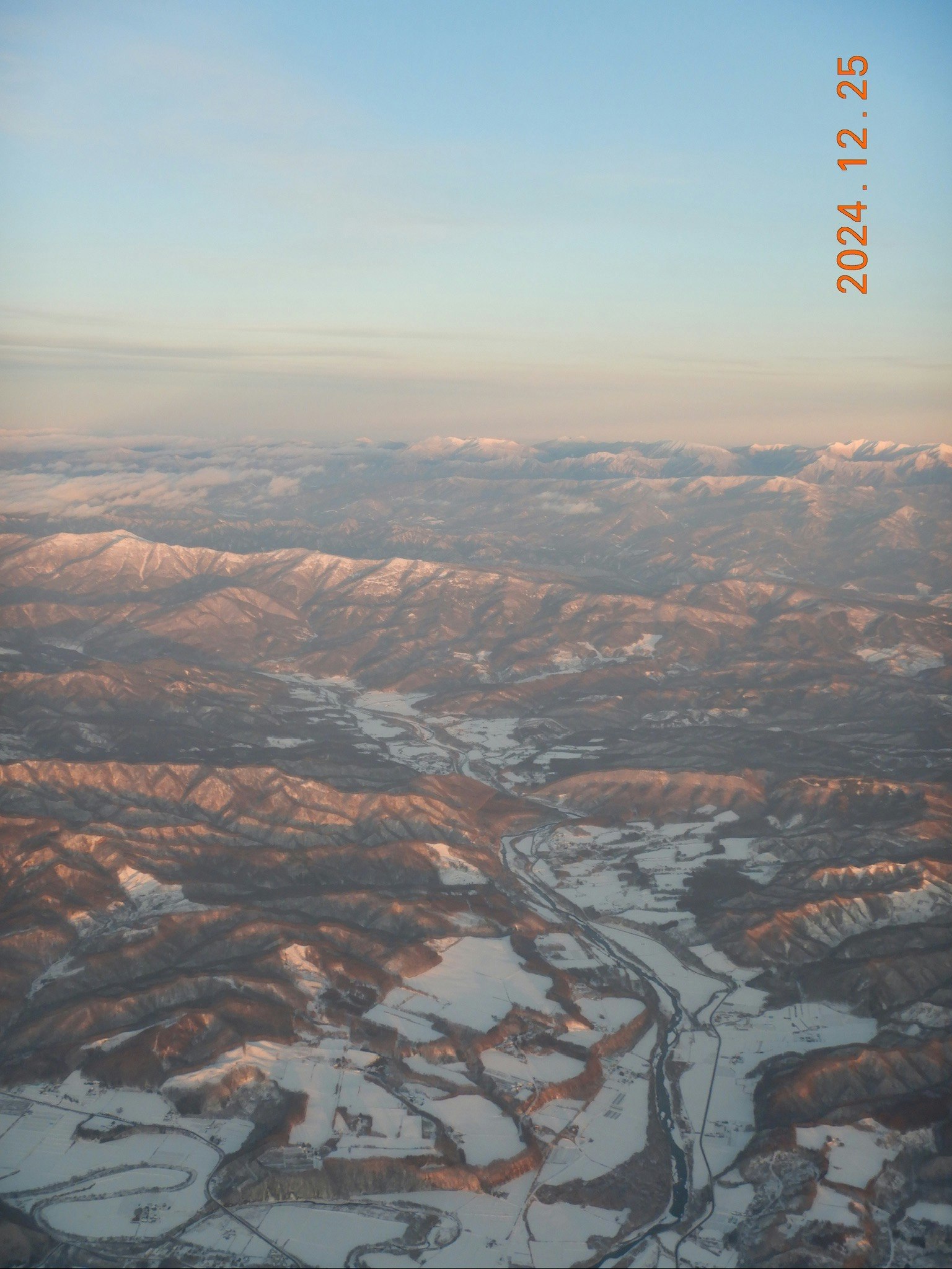 Vista aerea delle montagne dell’Hokkaido e di un fiume tortuoso al crepuscolo