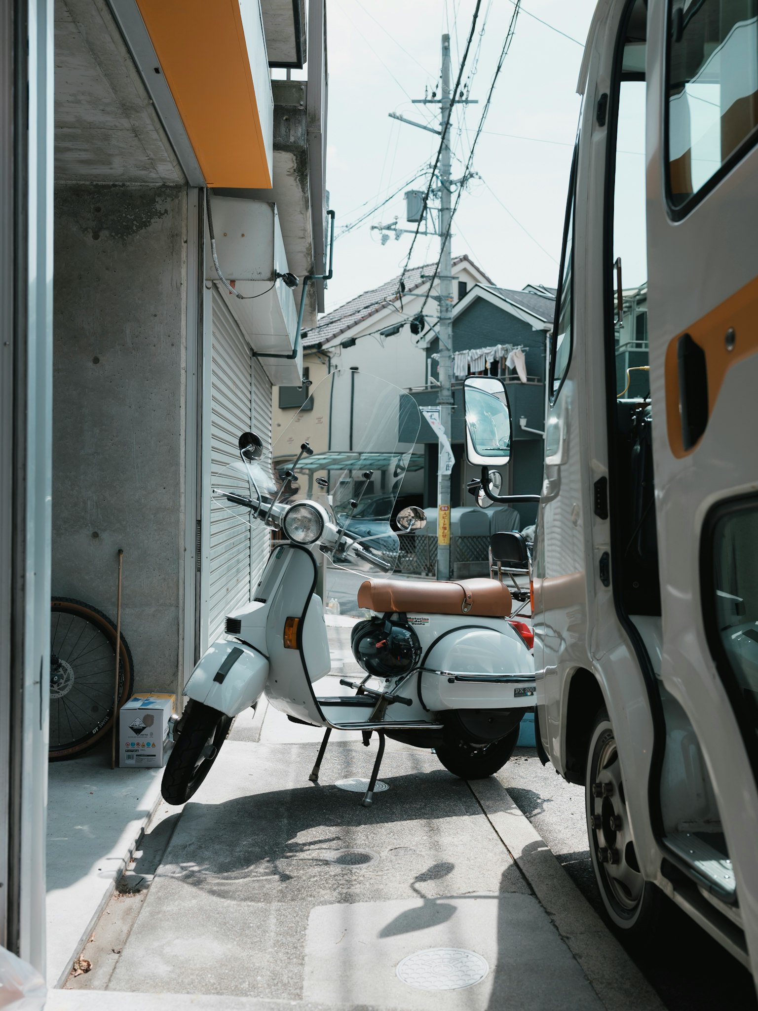 Immagine di uno scooter bianco parcheggiato in una strada stretta accanto a un autobus