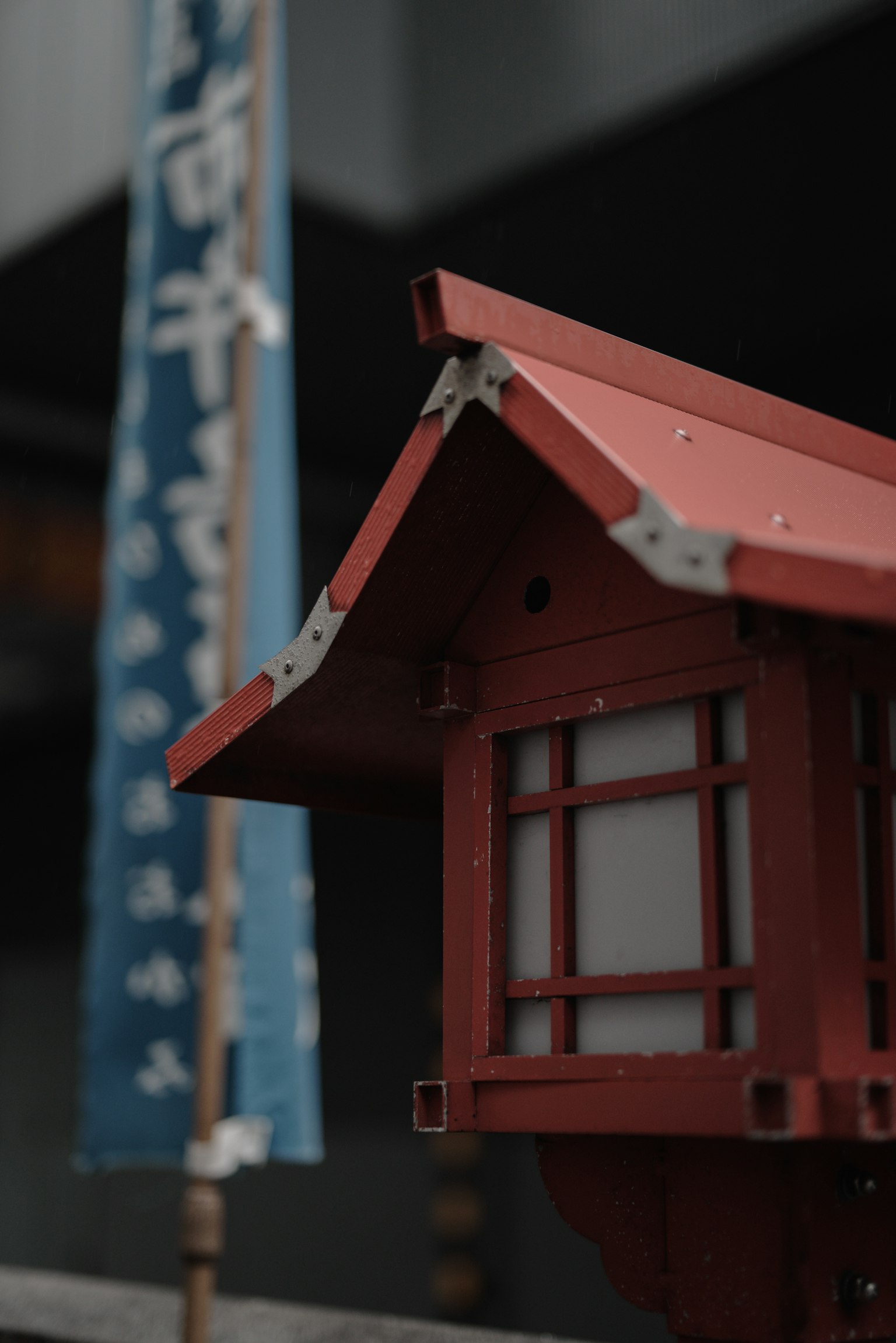 Pequeño edificio con techo rojo y una bandera azul de fondo