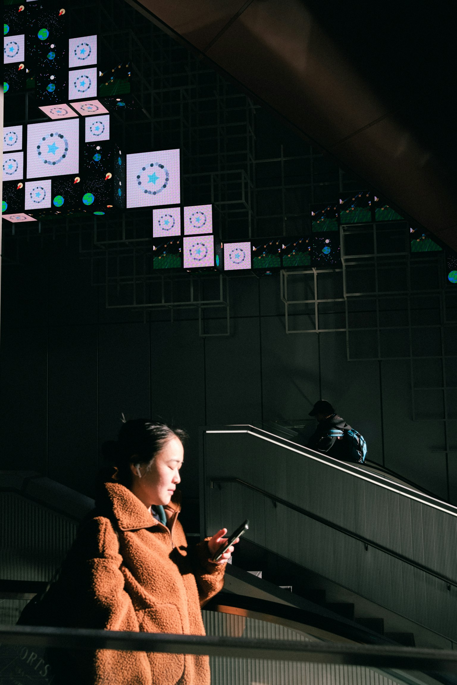 Woman on stairs looking at her phone with colorful display in the background