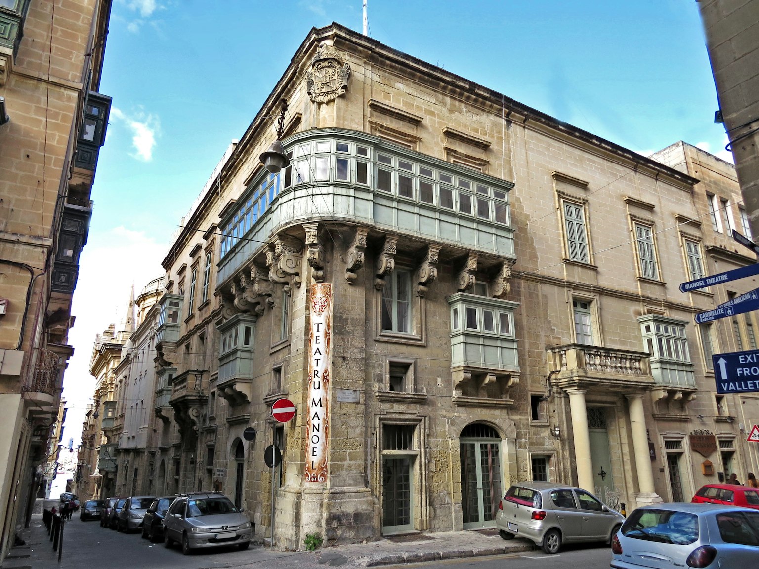 Bâtiment historique avec un balcon orné dans une rue étroite