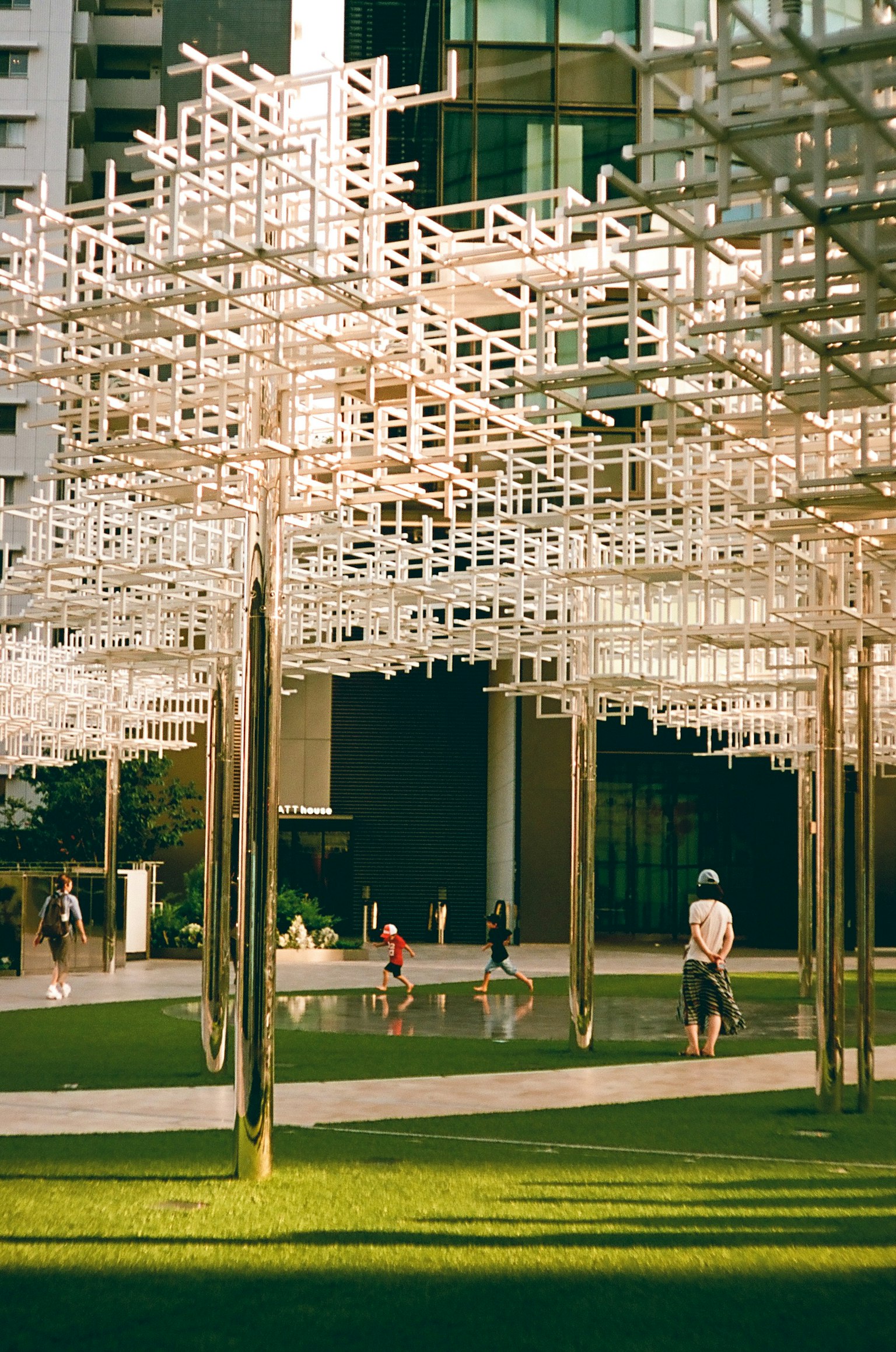 Personas jugando bajo una instalación estructurada blanca frente a un edificio moderno