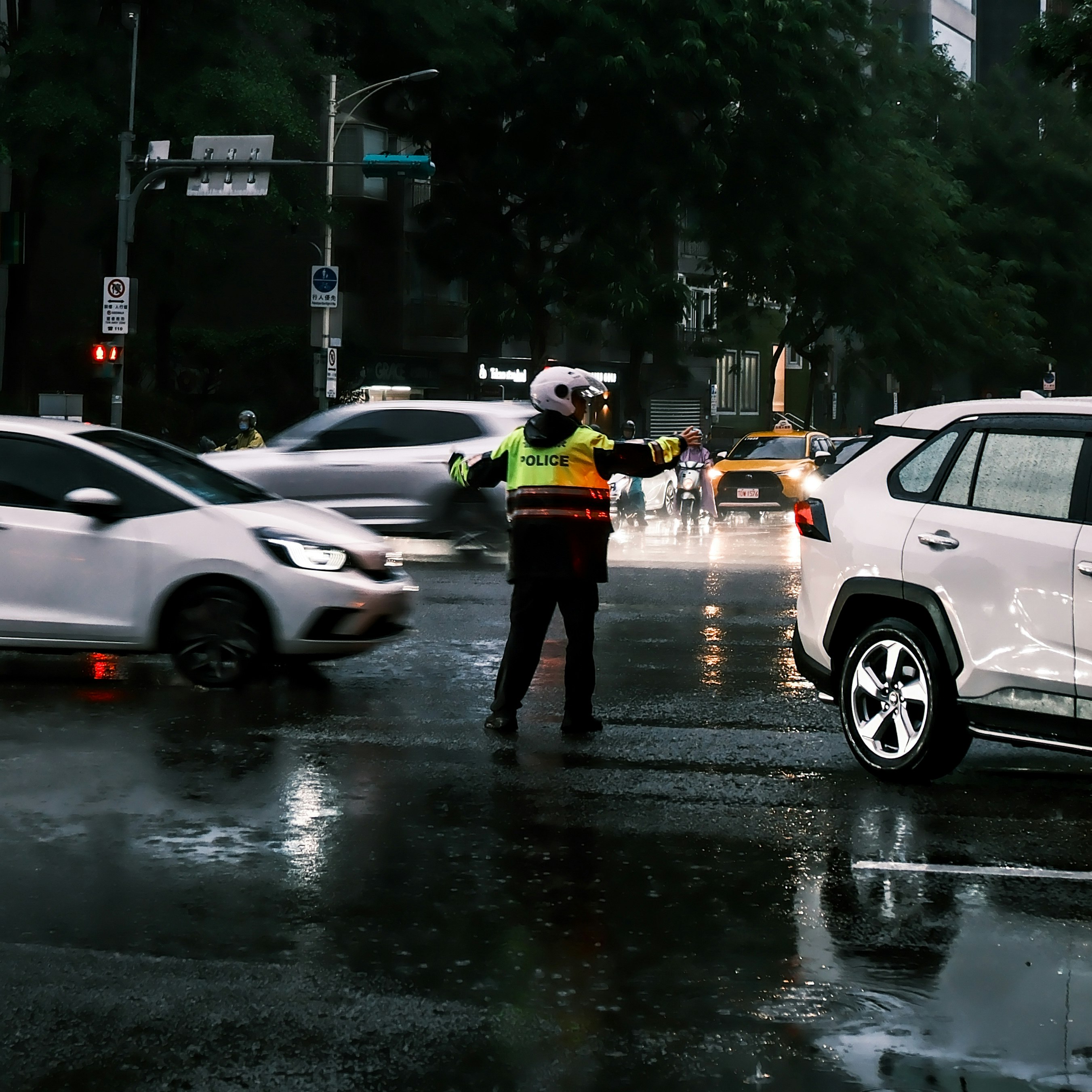 雨の交差点で交通整理する警察官の後ろ姿
