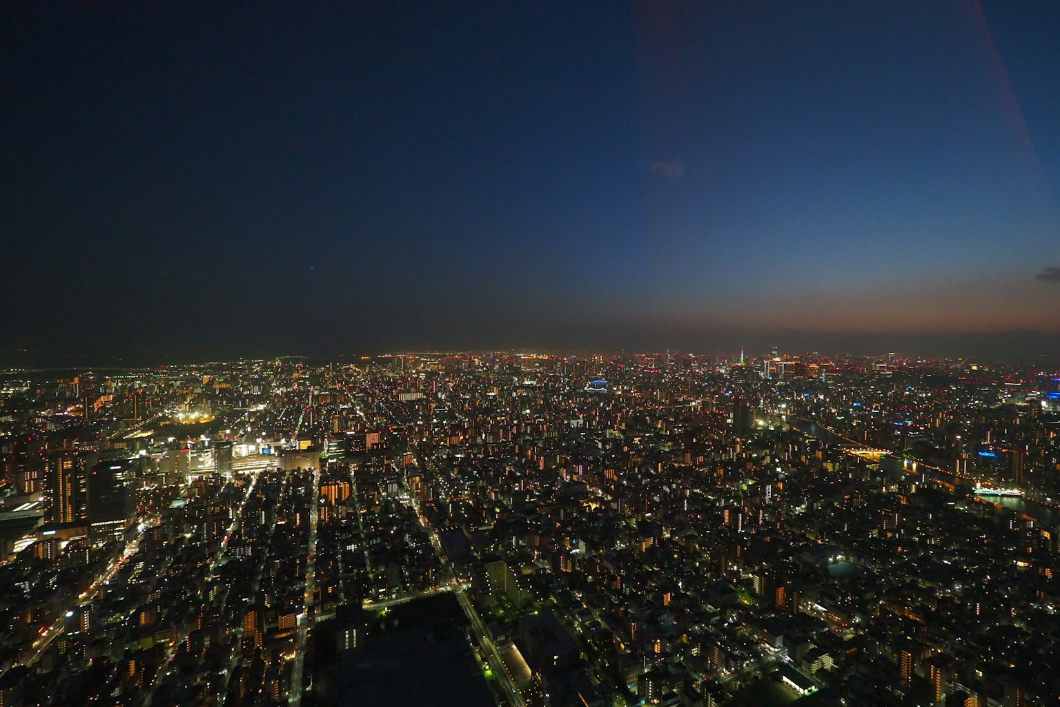 Panoramic view of Tokyo at night showcasing city lights and dark sky