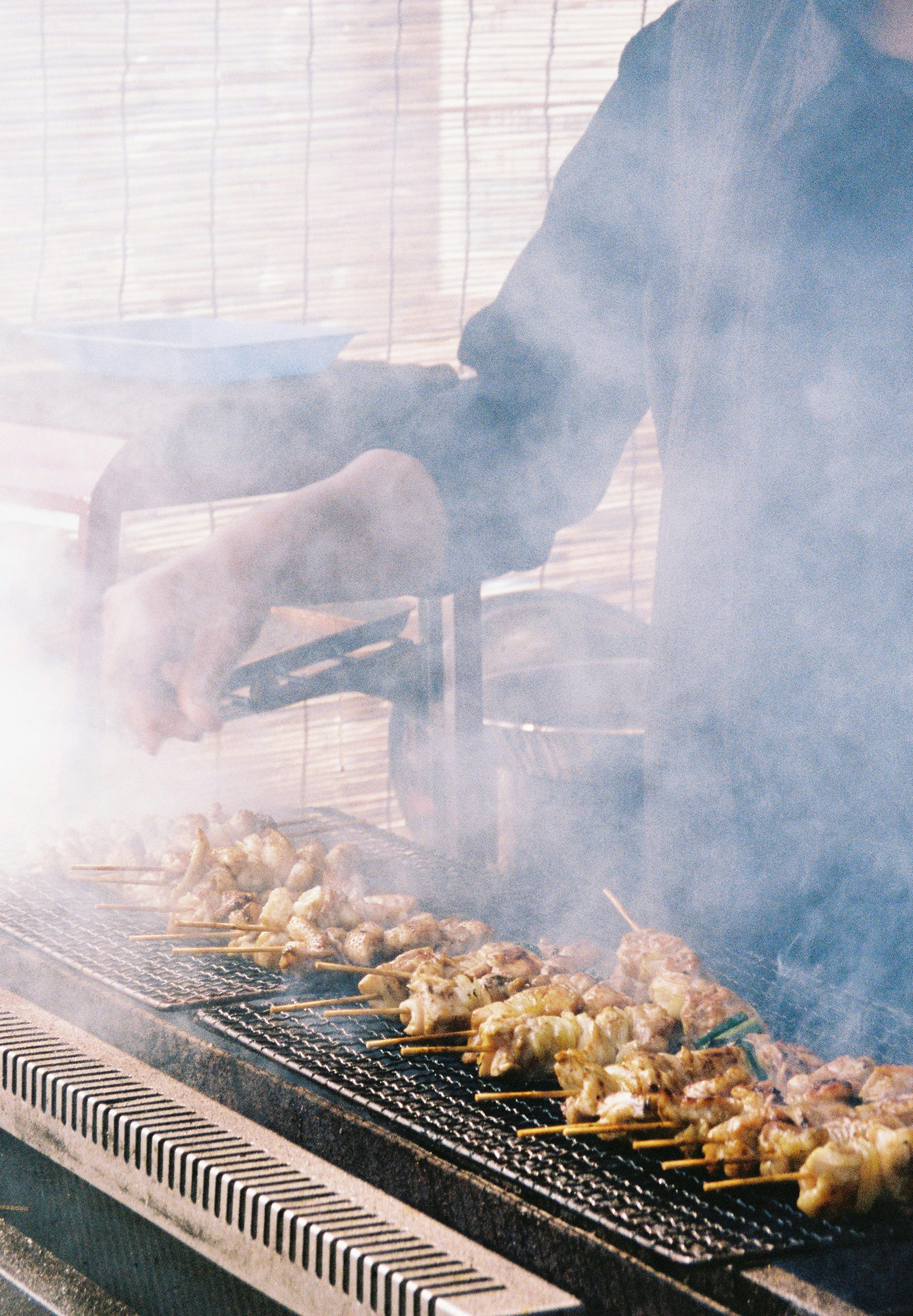 chicken skewers grilling on a smoky barbecue grill