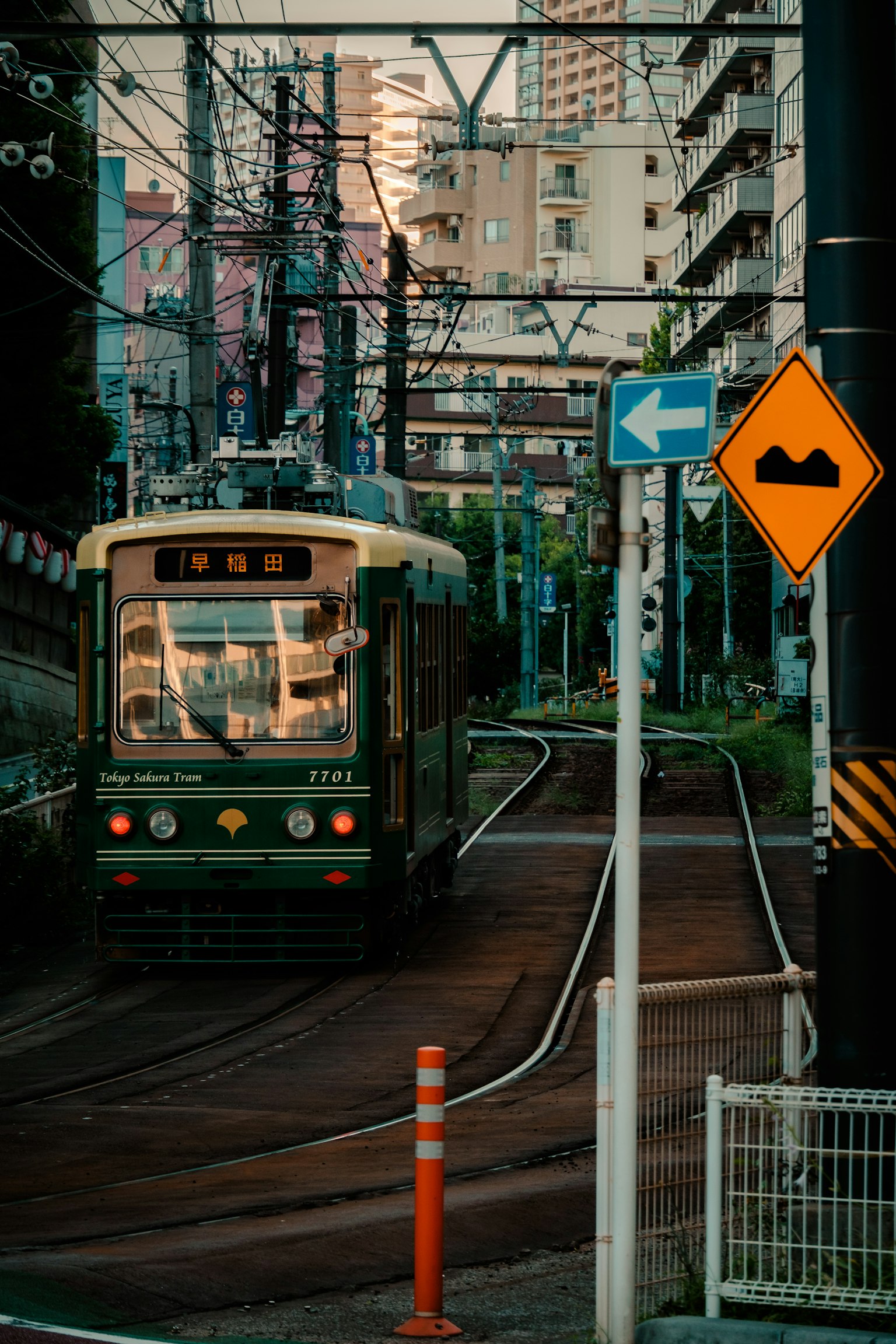 绿色有轨电车穿行于城市风景中夕阳的反射建筑和电线可见