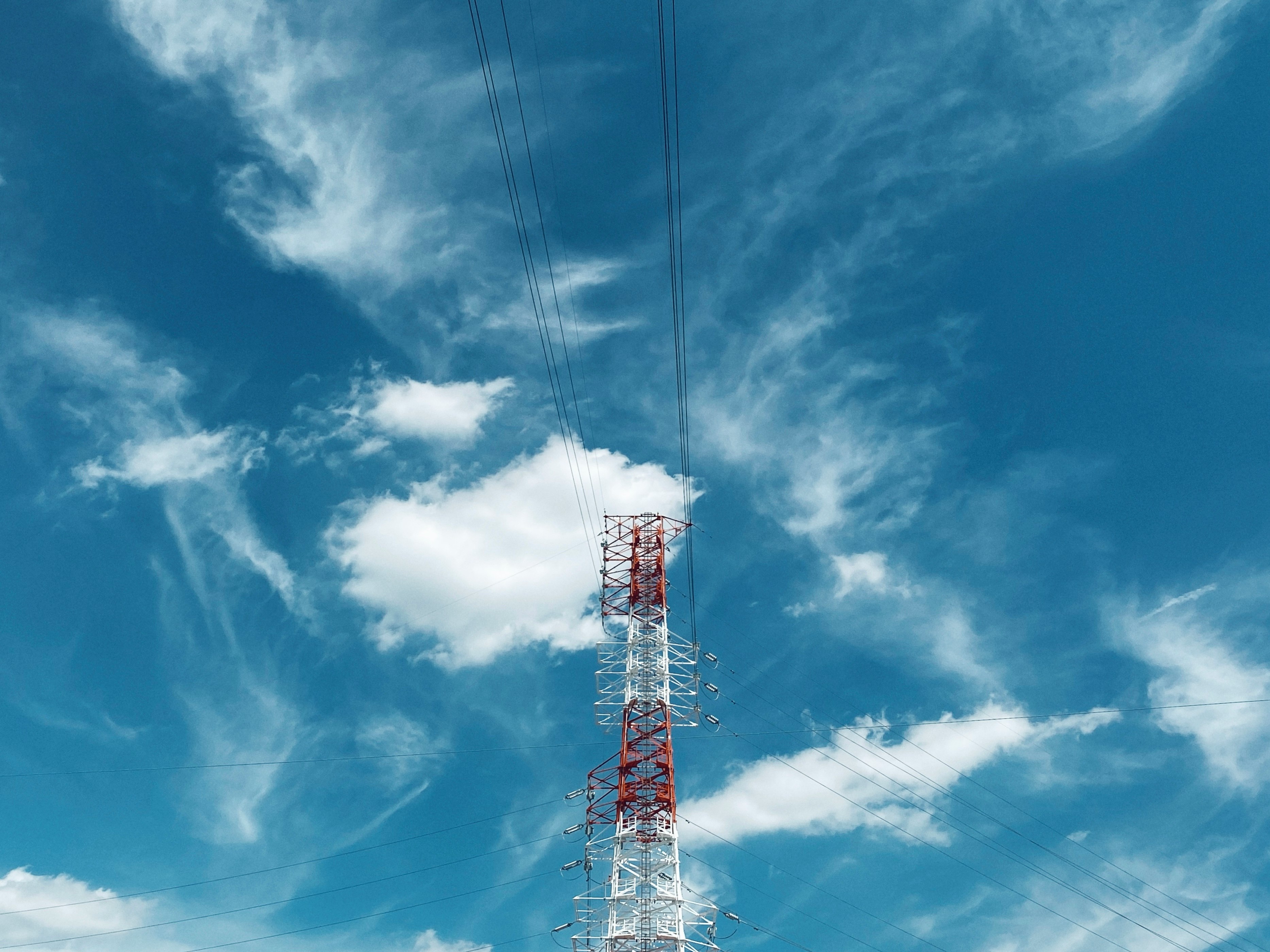 Stromübertragungsturm vor blauem Himmel mit Wolken