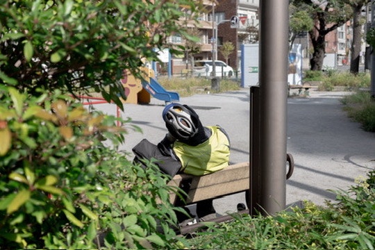 Una persona con un casco da bicicletta seduta su una panchina in un parco