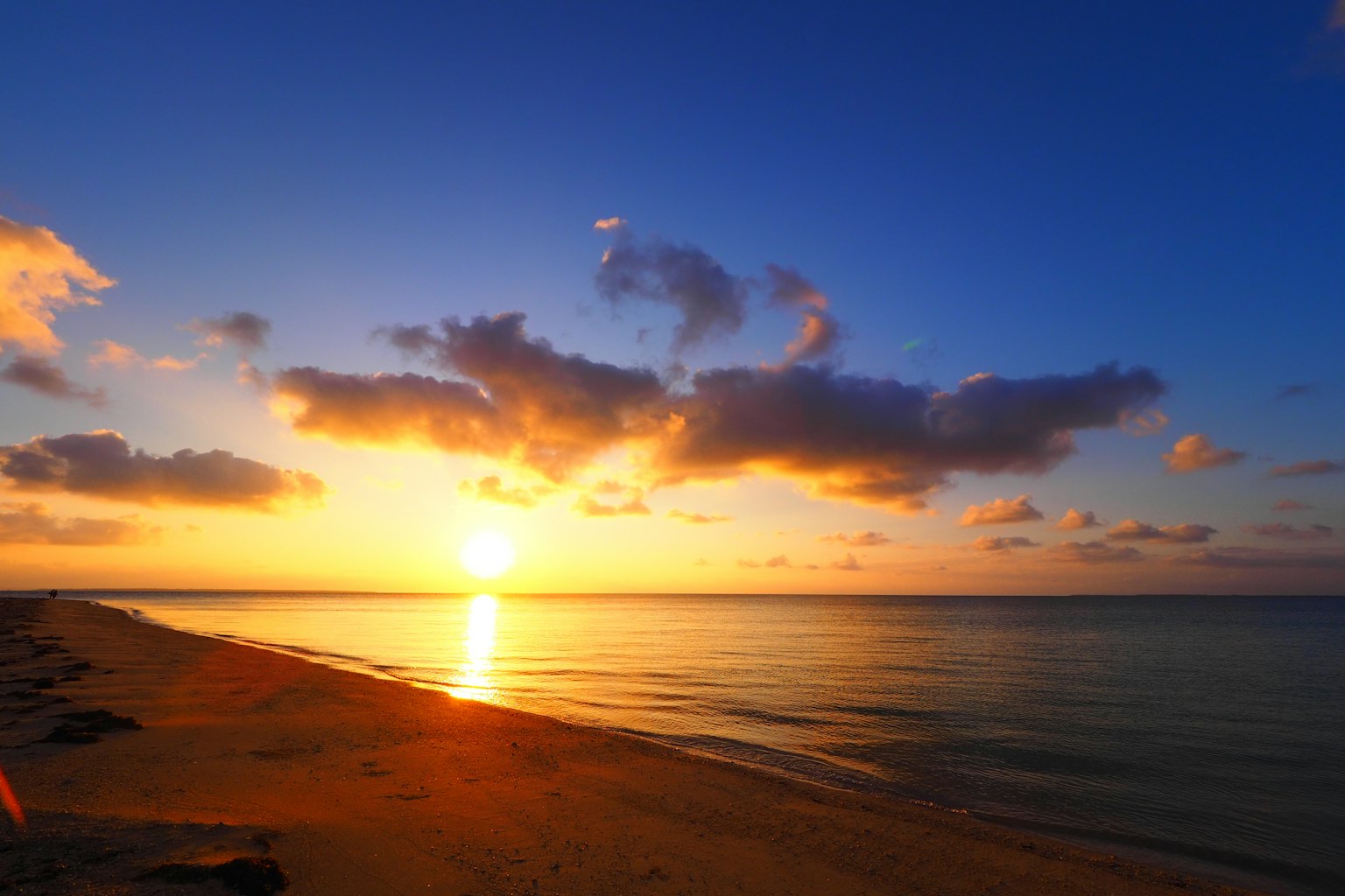 Beach landscape with sunset over the ocean blue sky and clouds