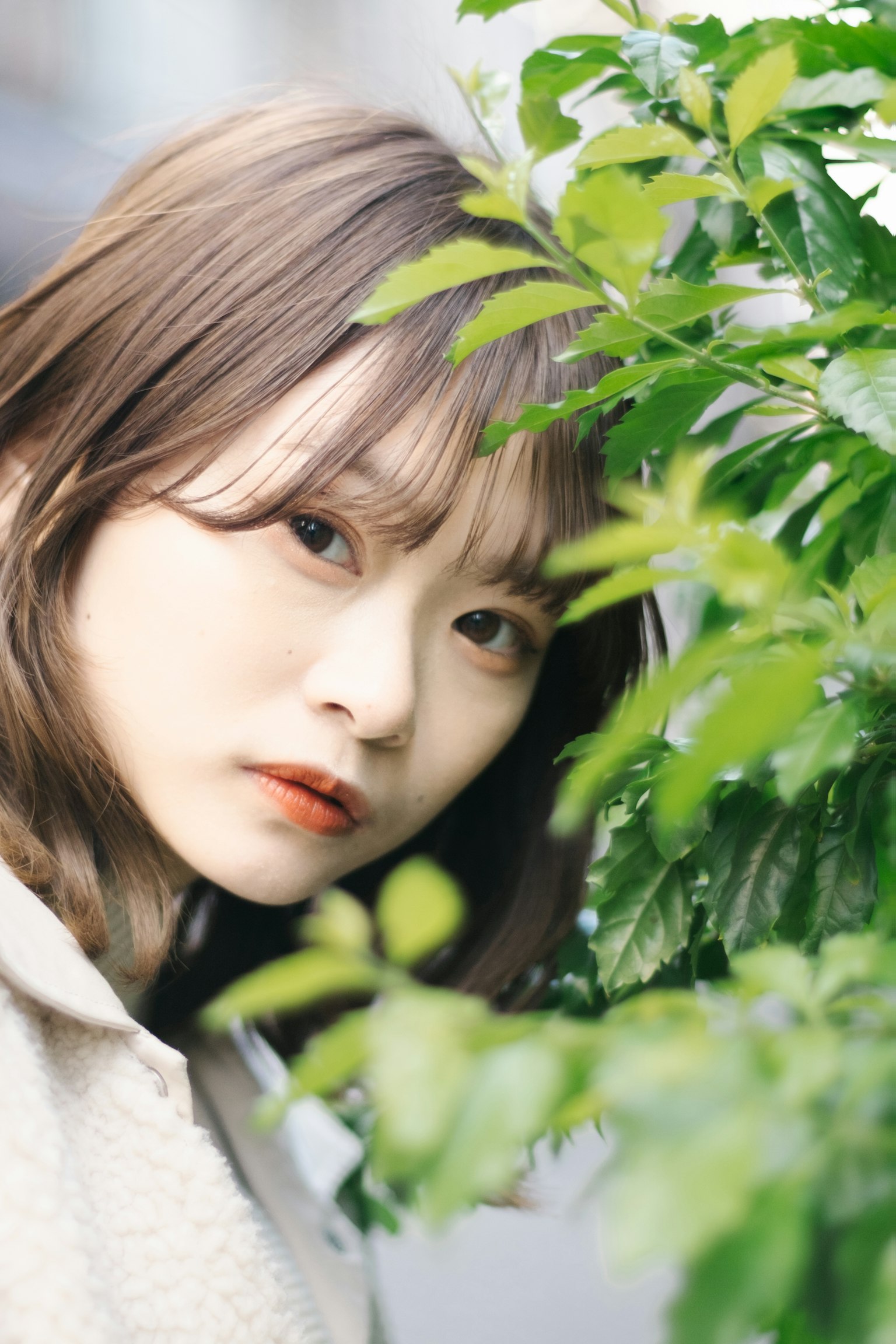 หญิงสาวใกล้ใบไม้สีเขียวมีสีหน้าอ่อนโยน