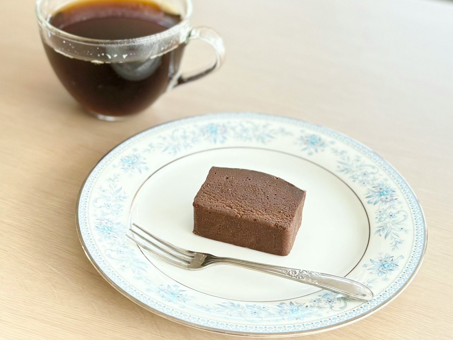 Una tazza di caffè accanto a una torta al cioccolato su un piatto decorativo