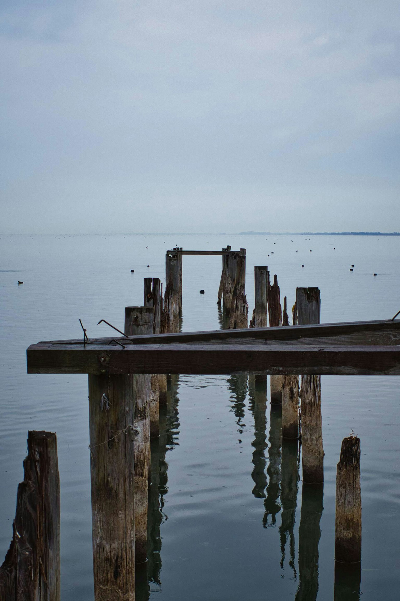 Überreste eines alten Piers im ruhigen Wasser reflektiert