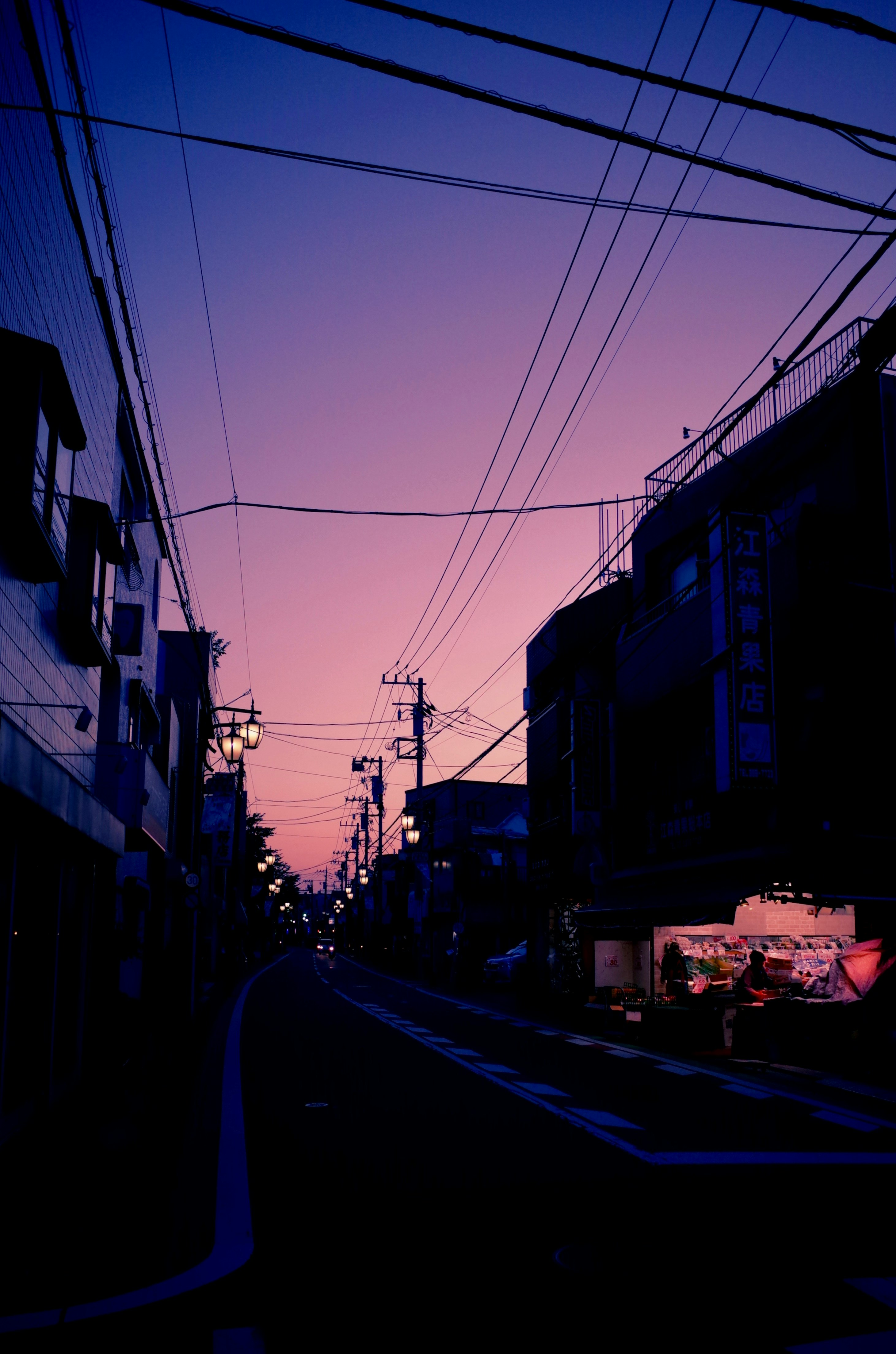 夕暮れの路地に伸びる電線と街並み