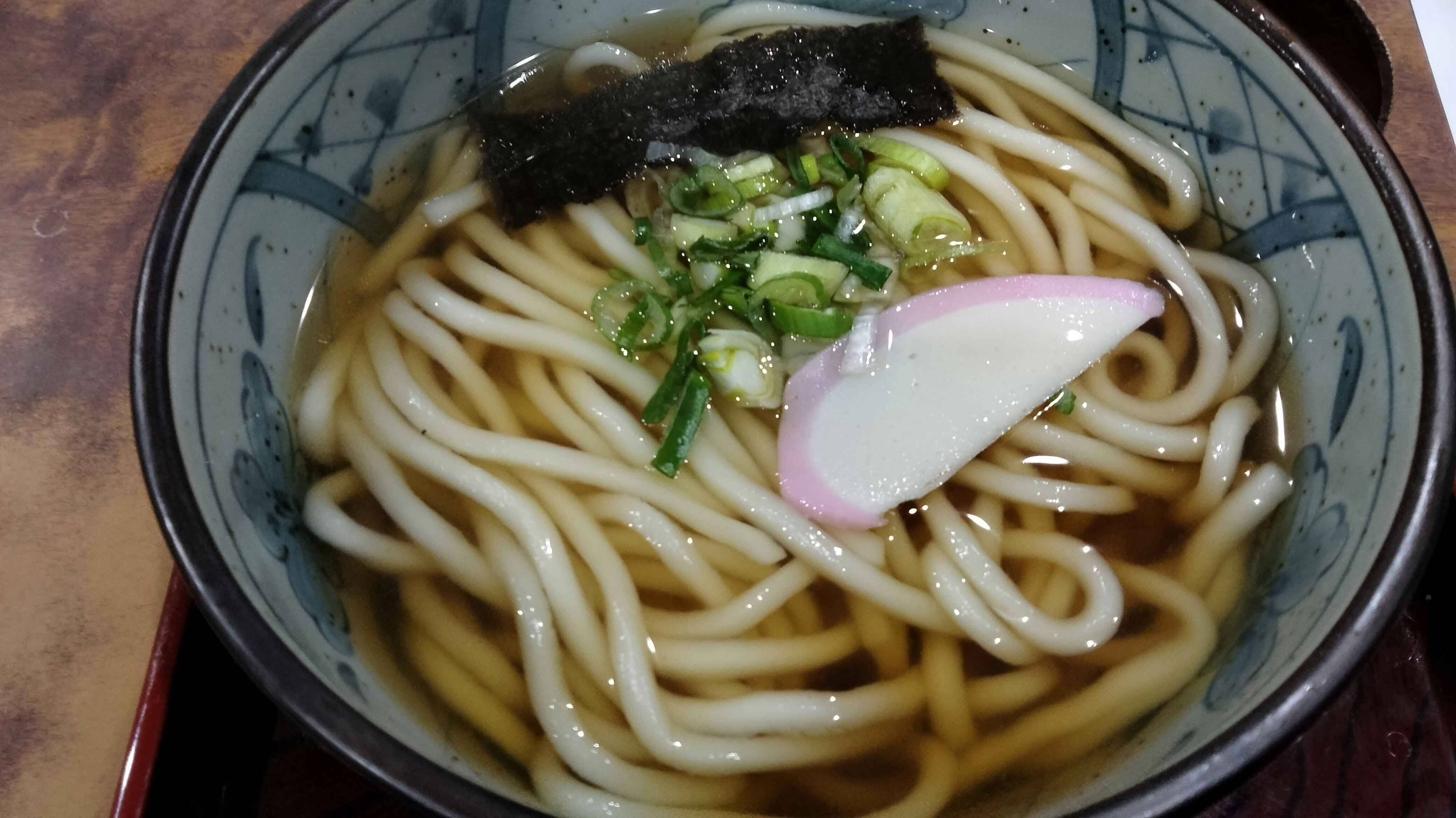 器に盛られたうどんと刻みねぎ、かまぼこ