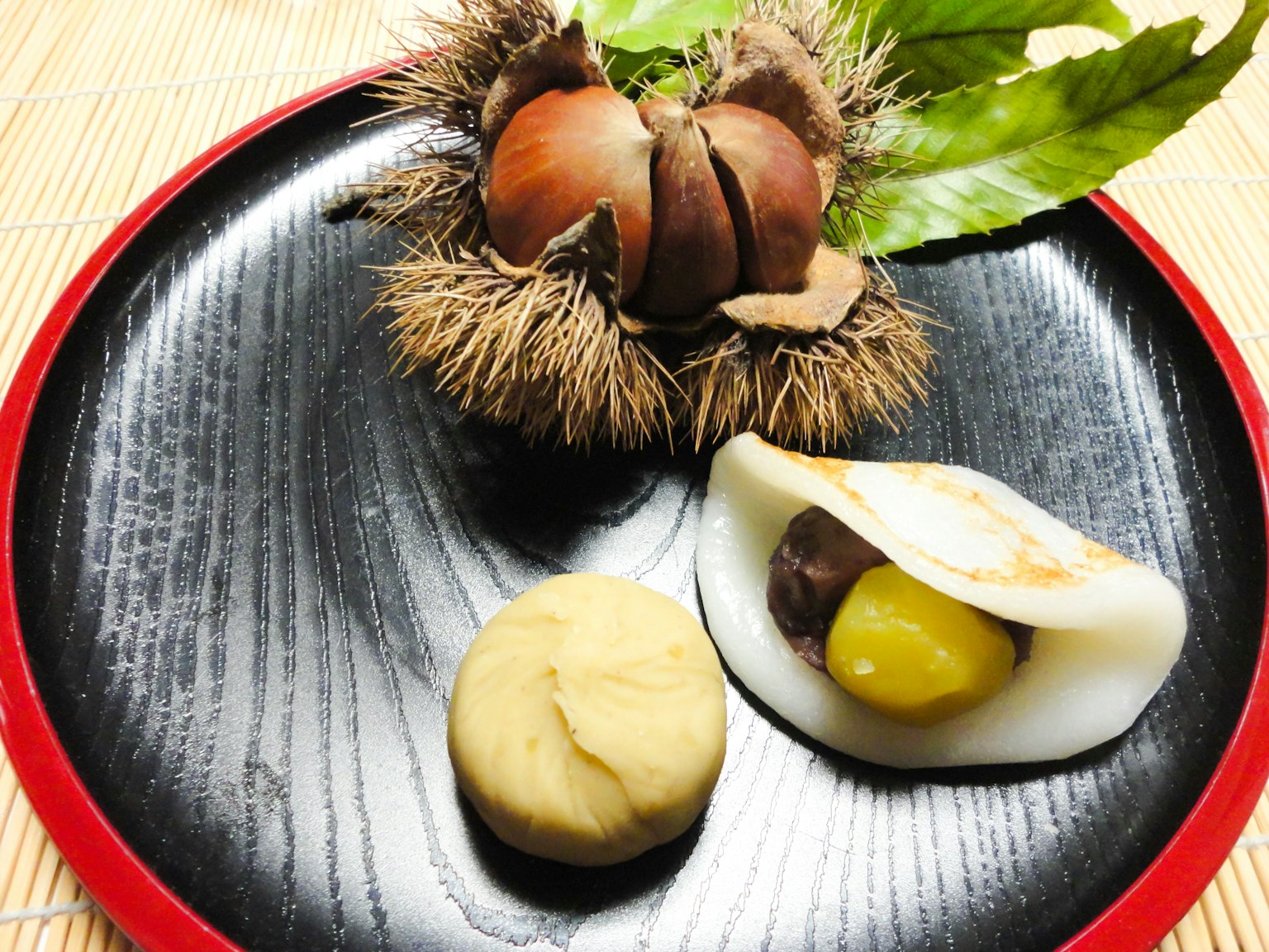 Un piatto nero con castagne e dolci giapponesi tradizionali