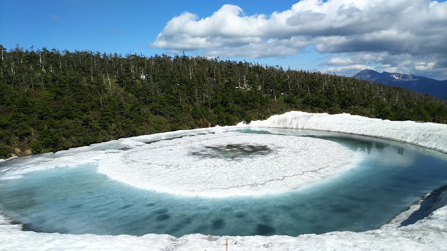 环形冰川湖泊，蓝色水域，四周被郁郁葱葱的森林环绕