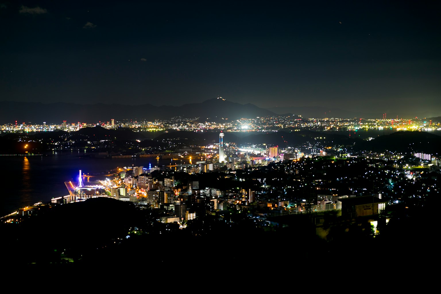 Vista nocturna de una ciudad con edificios iluminados y reflejos en el agua