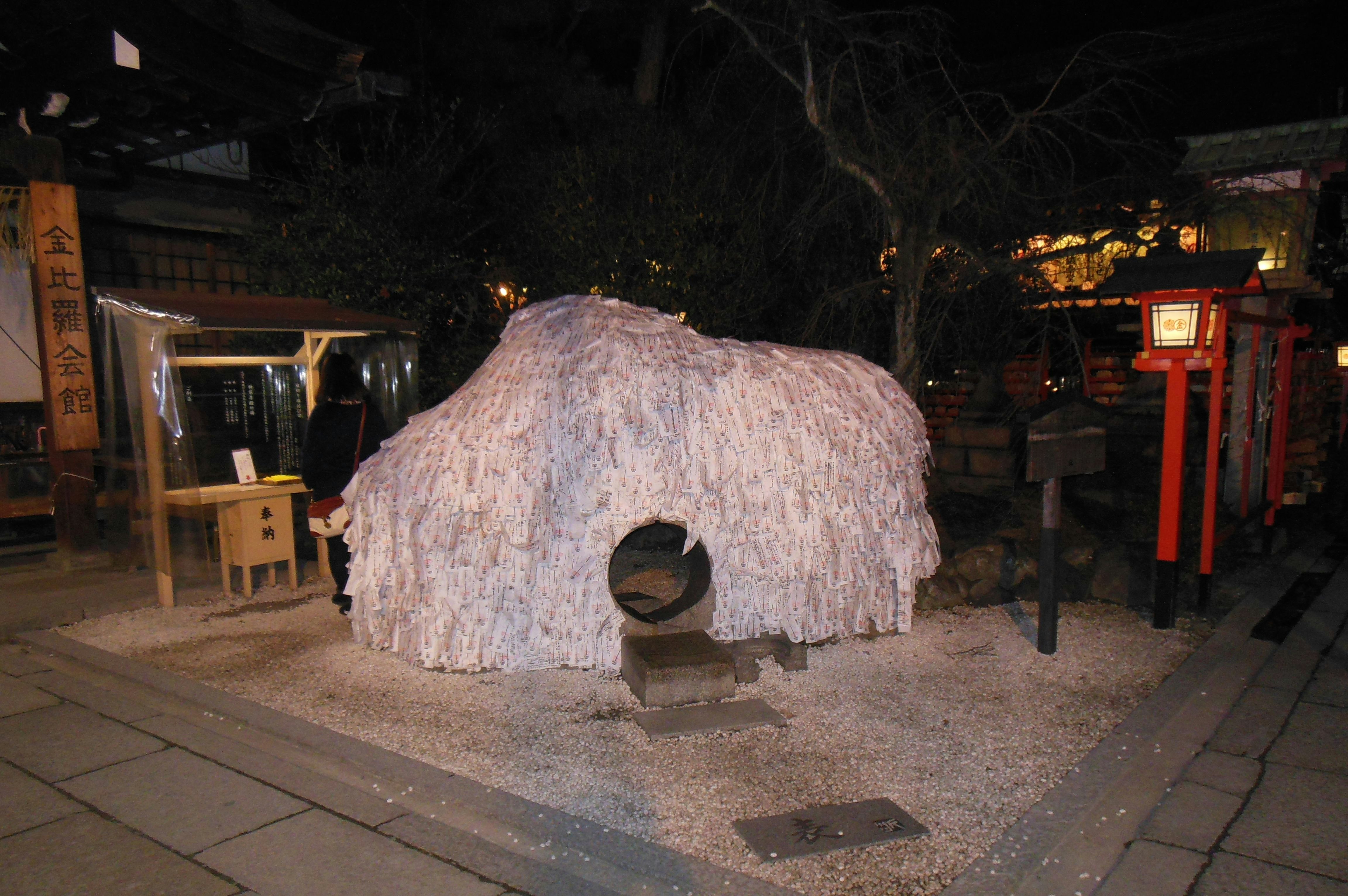 white hut-shaped sculpture and stone pedestal in a night alley