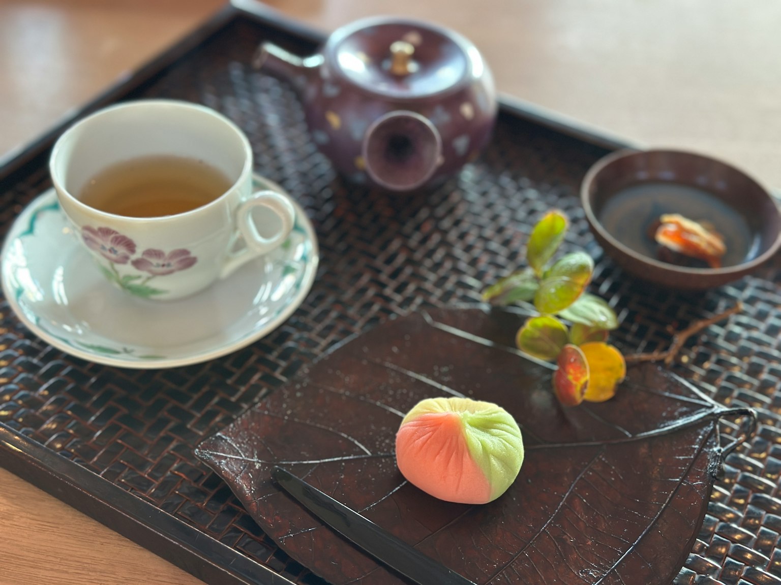 Cangkir teh dan teko dengan makanan manis Jepang di atas nampan