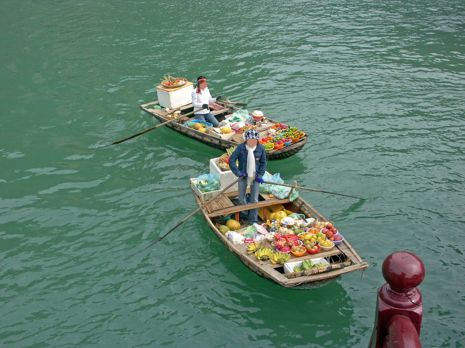 Zwei kleine Boote, die auf dem Wasser schwimmen und Früchte verkaufen