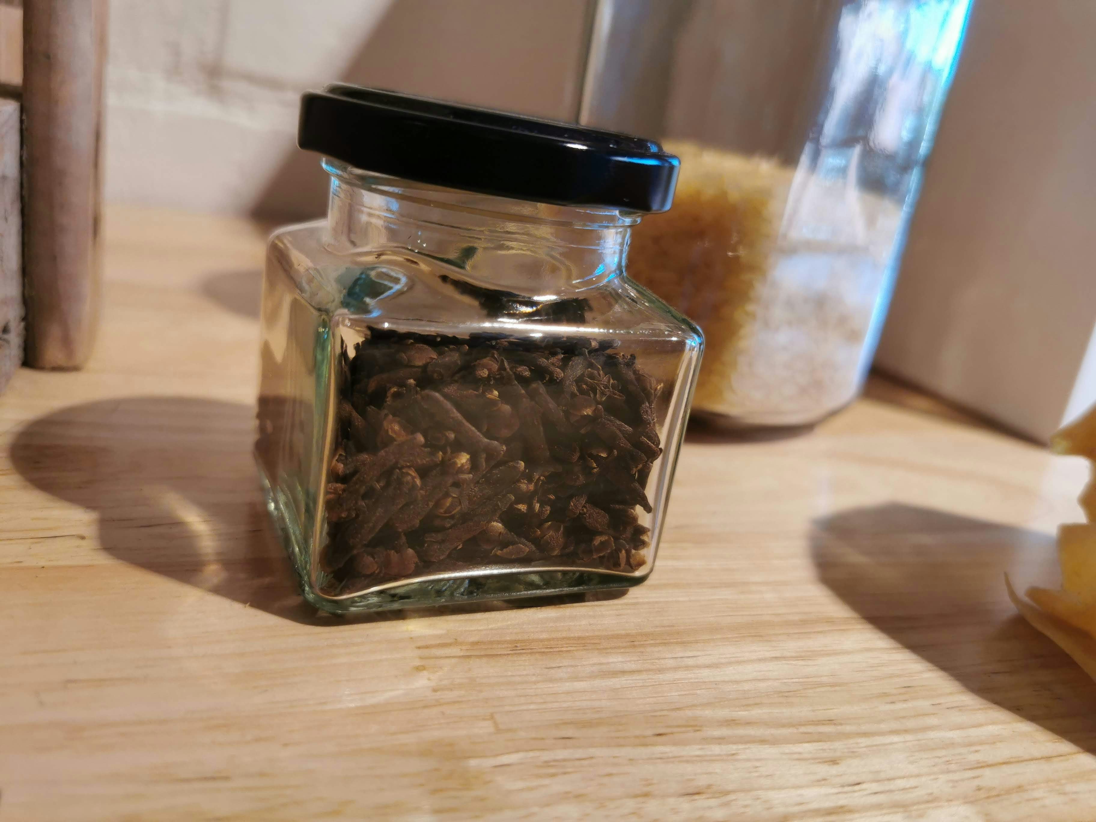bocal en verre avec des herbes séchées sur une table en bois