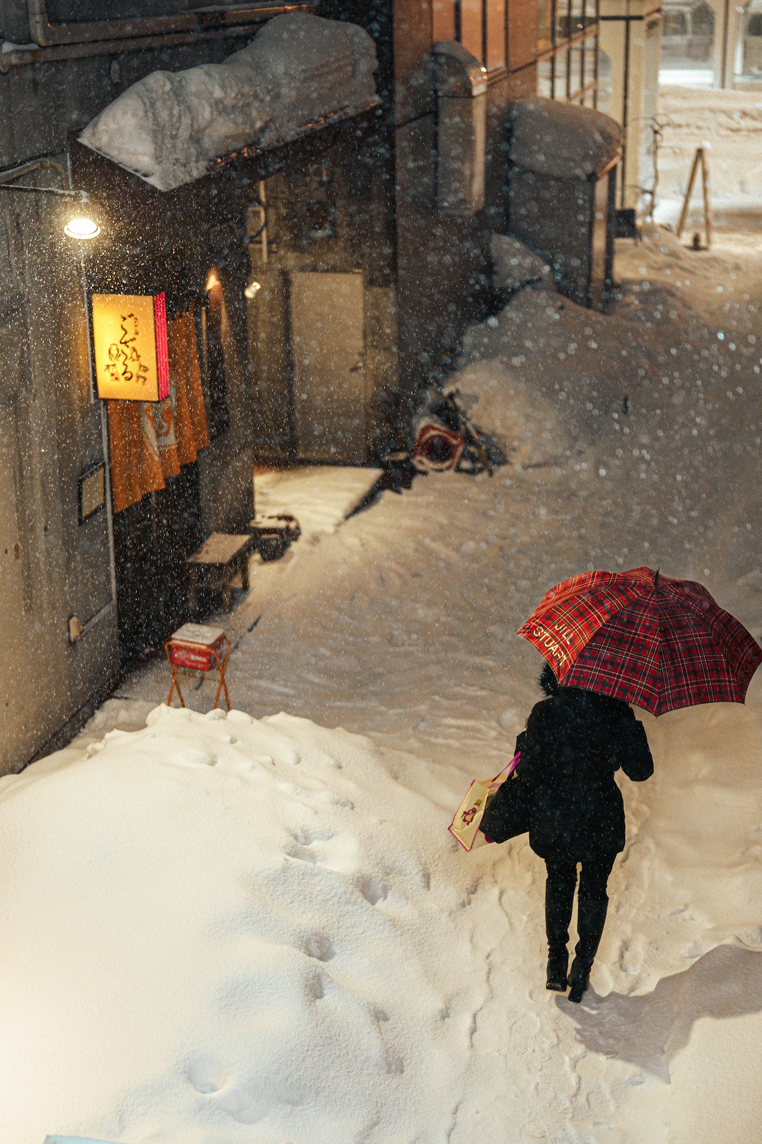 在雪中行走的人和紅色格子傘