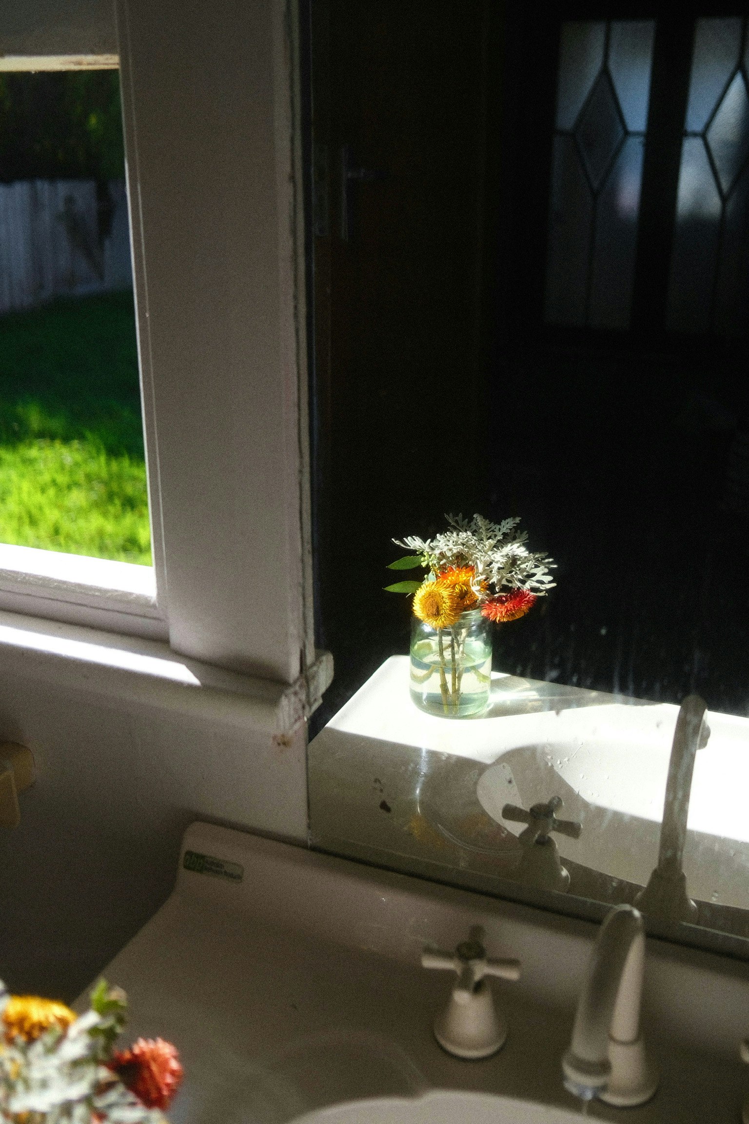窓からの自然光が差し込む洗面所に置かれた花瓶の花