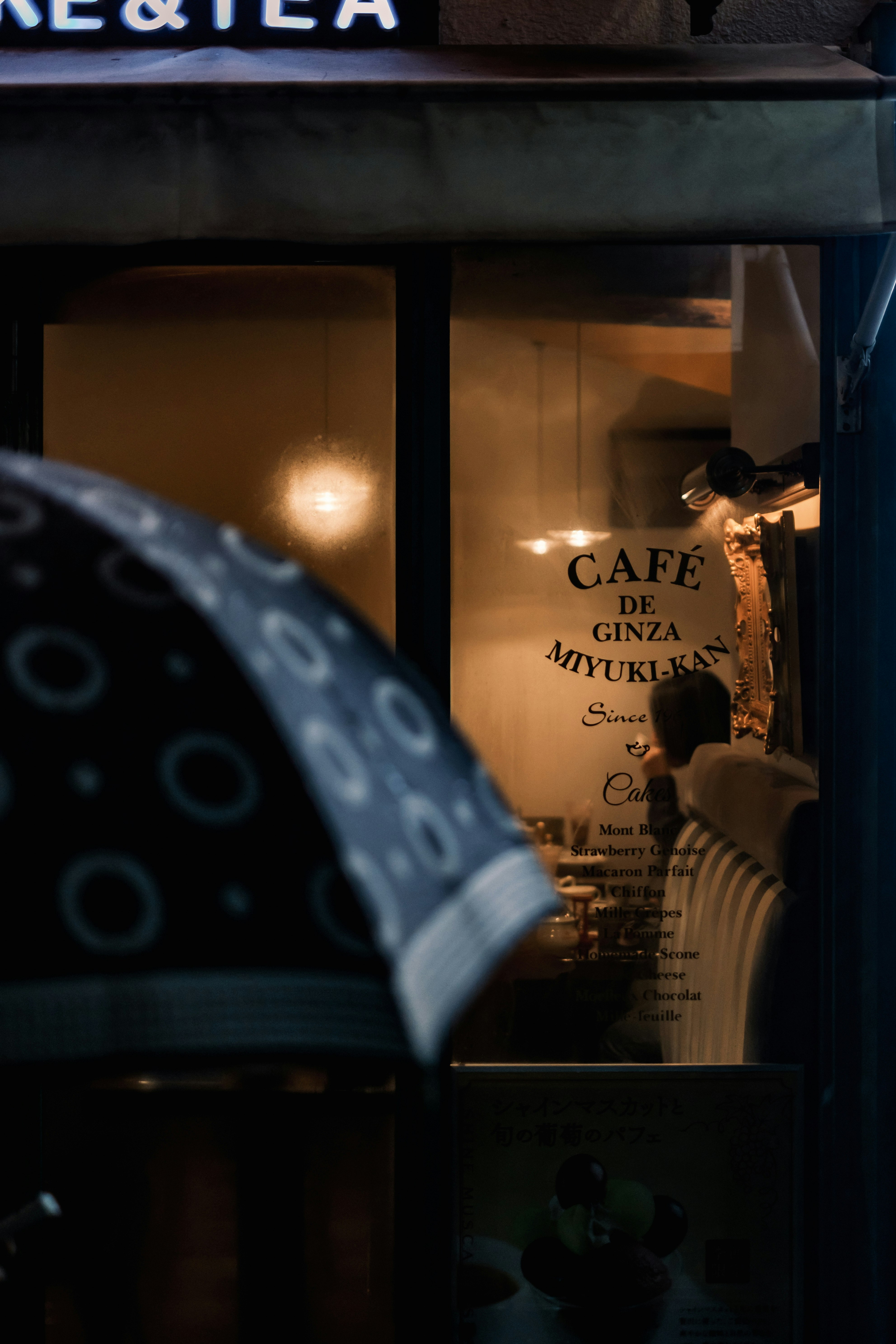 雨の路地にある「CAFE DE GINZA MITSUKAN」看板のあるカフェ入口