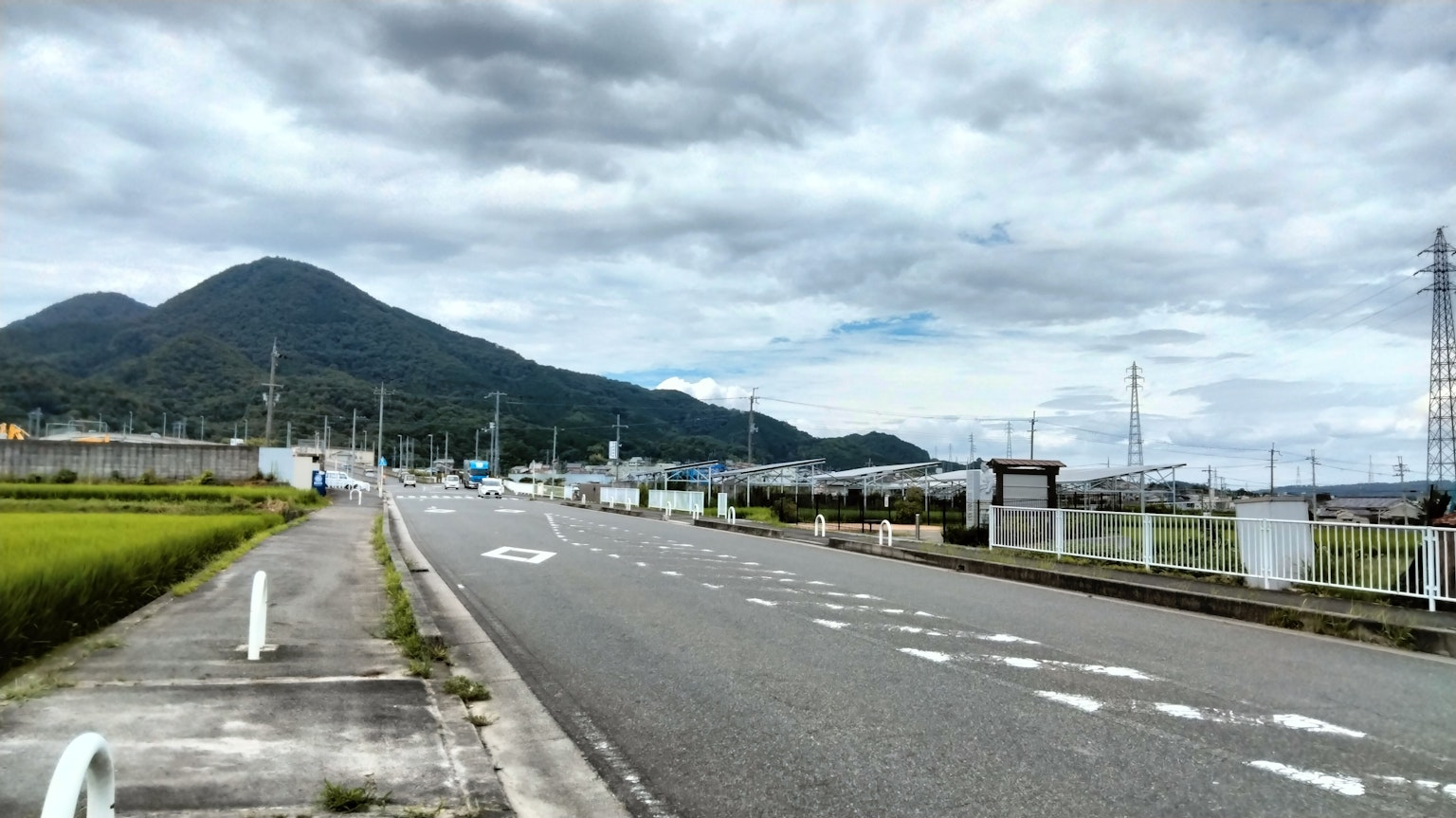 Ruhige Straßenszene mit Reisfeldern und Bergen im Hintergrund