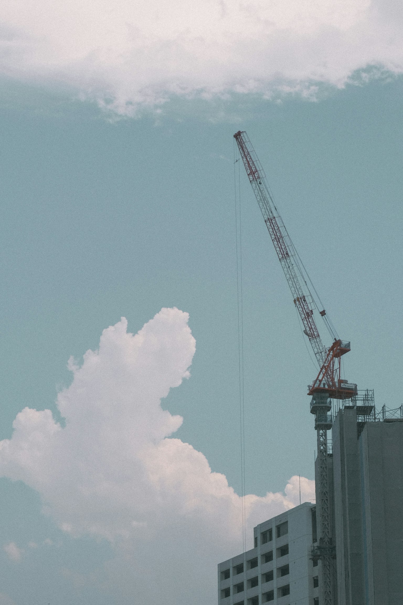 Crane menjulang di bawah langit biru dengan awan