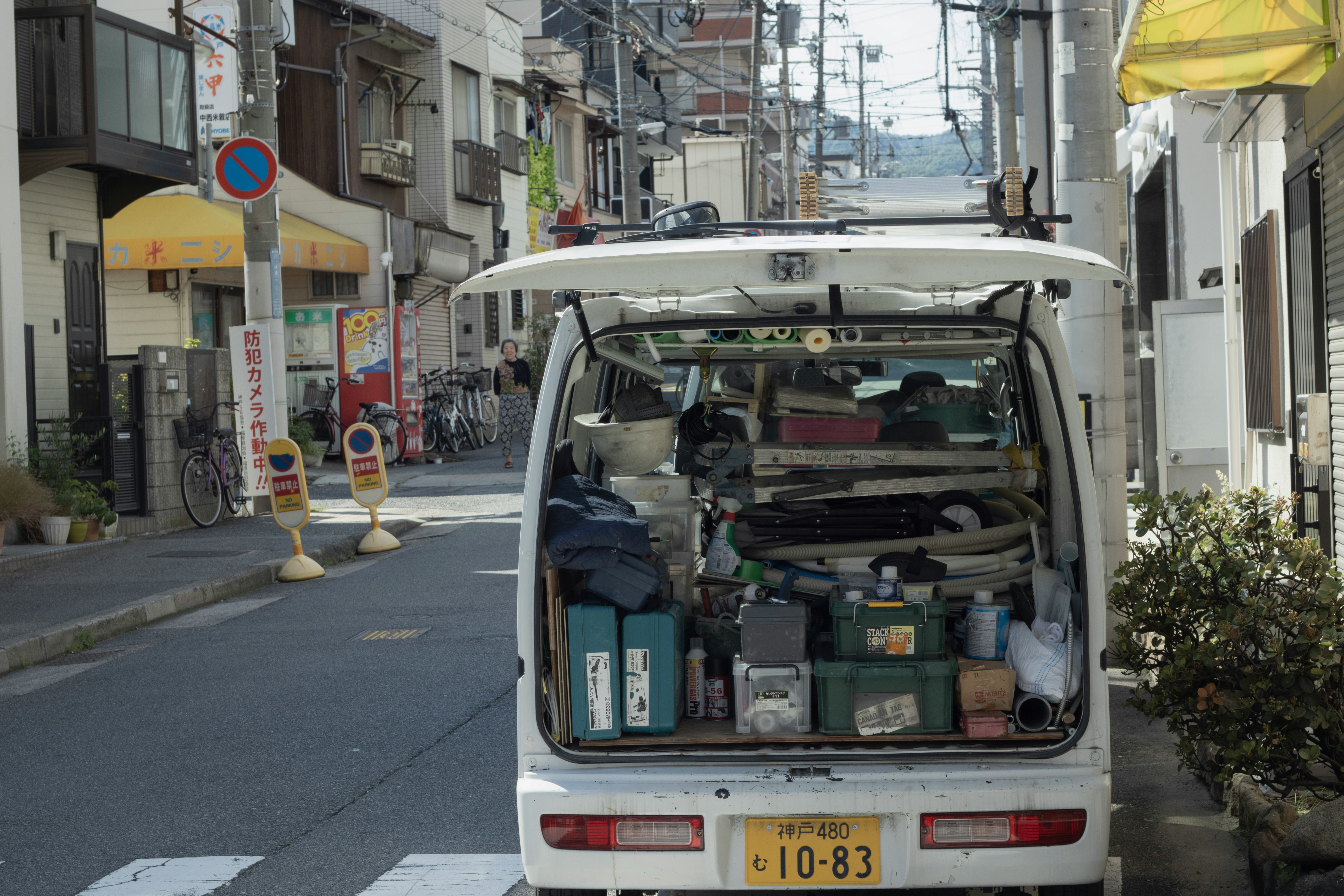 路地で停車した軽トラックの荷台に積まれた家財道具