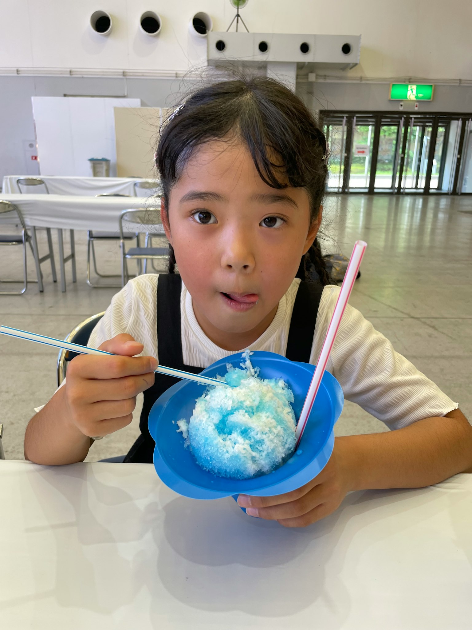 Ragazza con espressione sorpresa che tiene una ciotola blu di ghiaccio tritato