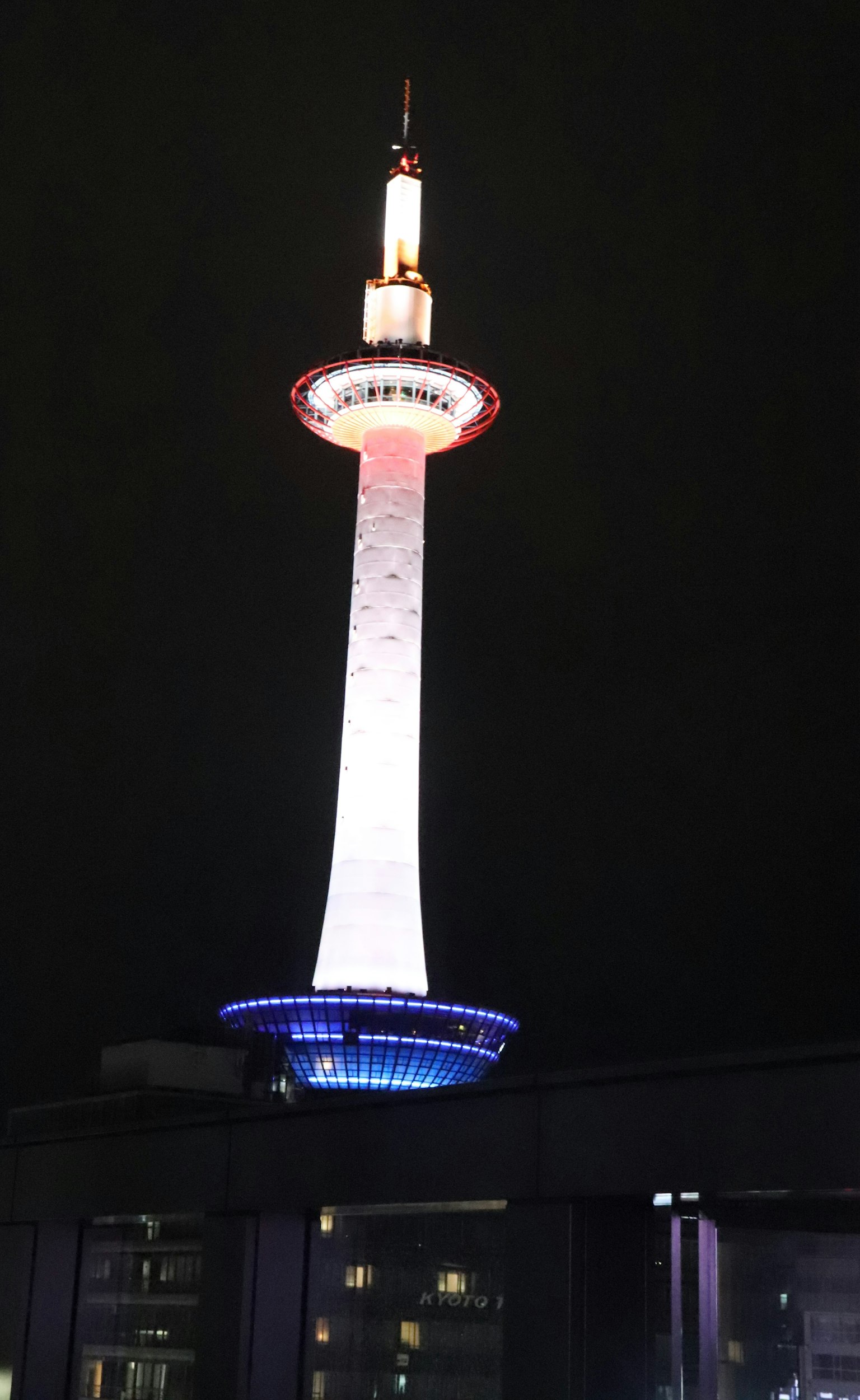 Menara Kyoto di malam hari diterangi lampu merah putih dan biru
