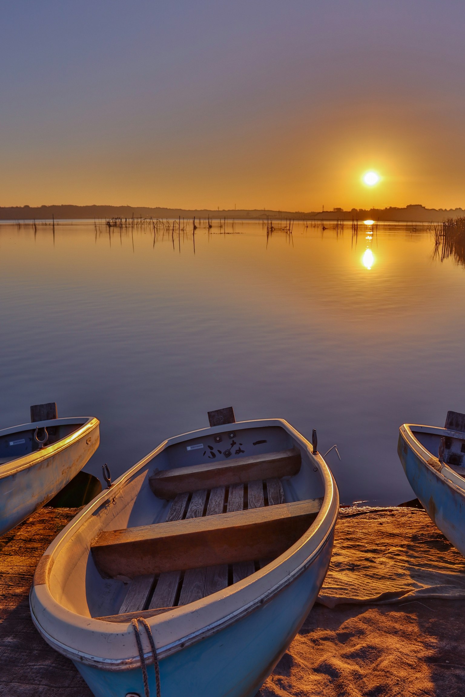 Rowboats by a calm lake at sunset with reflections