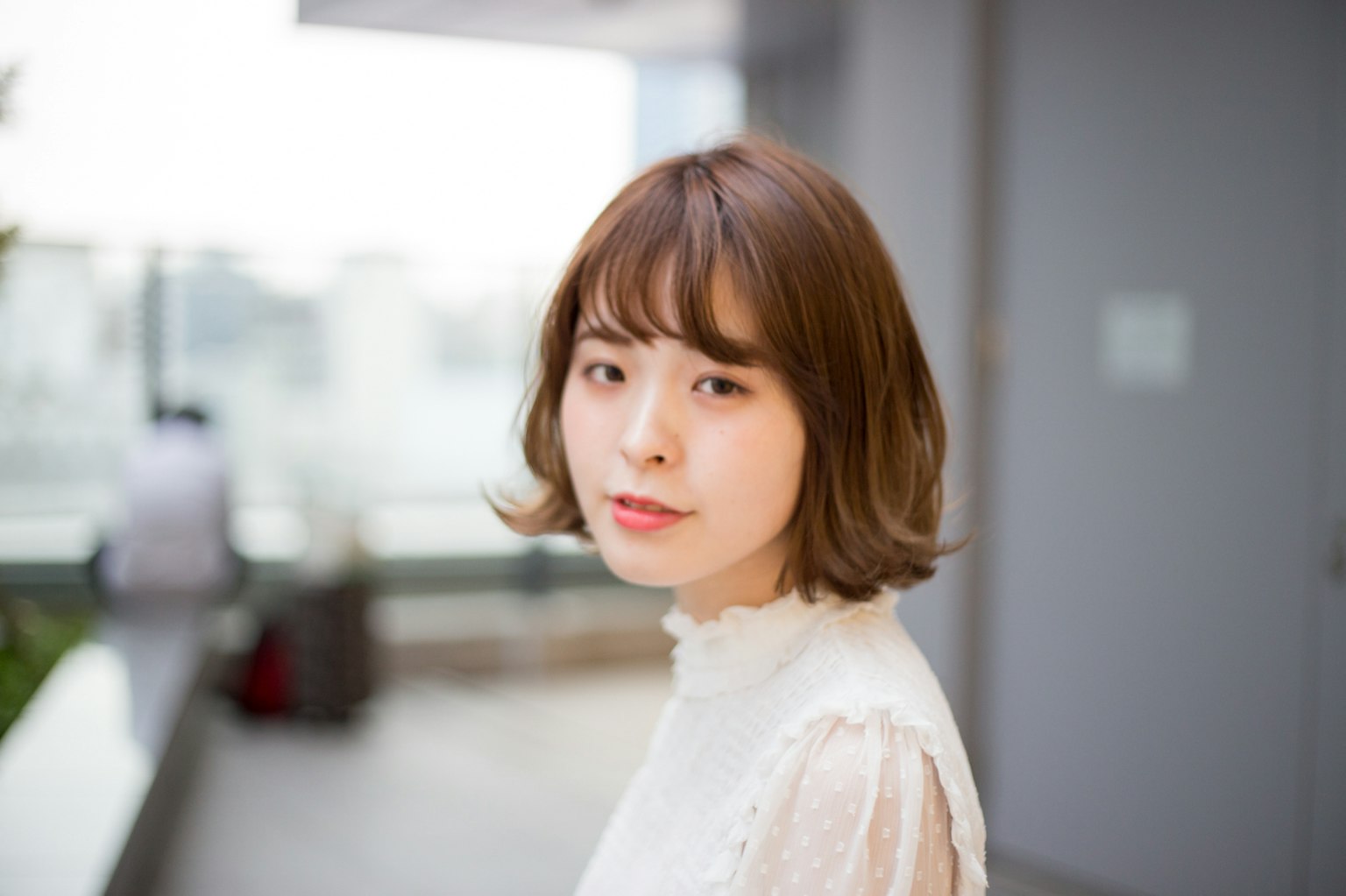 一位短髮女性穿著白色襯衫看著鏡頭