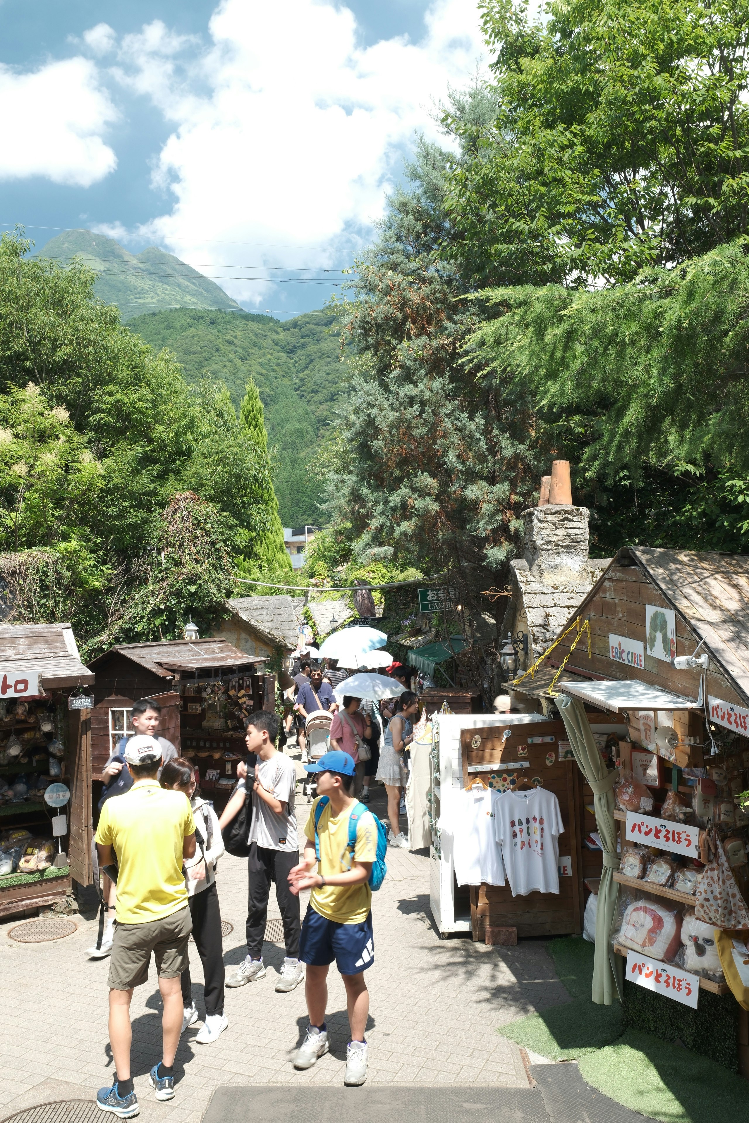 由布市・湯布院の山あいの観光通りを歩く人々と屋台