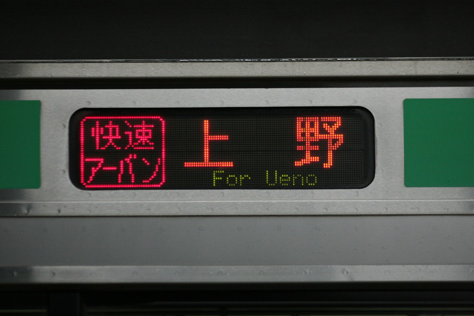 Panel de tren para Ueno con caracteres rojos que dicen 'Rápido Urbano'