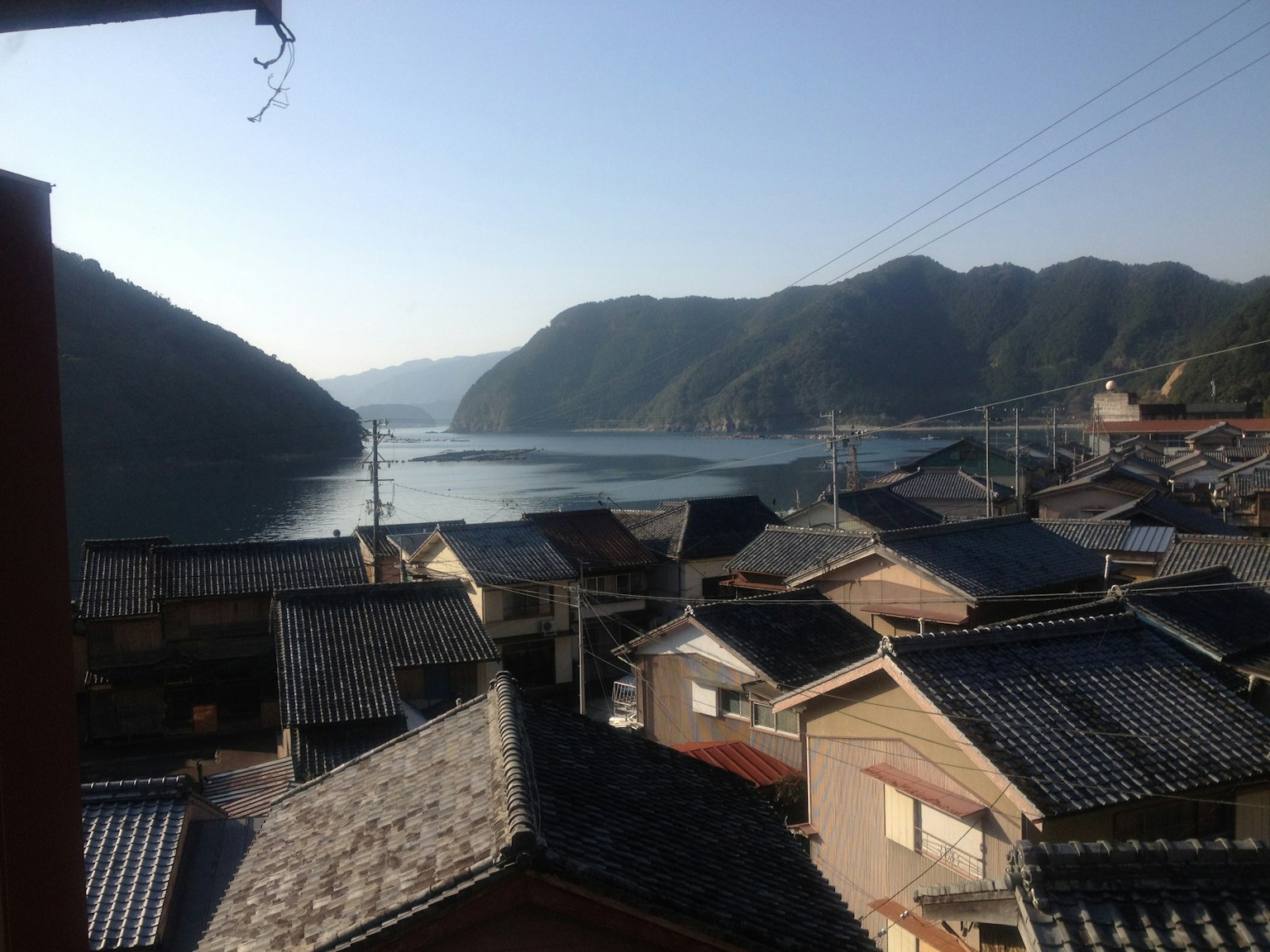 Vista di un villaggio giapponese tradizionale con mare calmo e montagne sullo sfondo