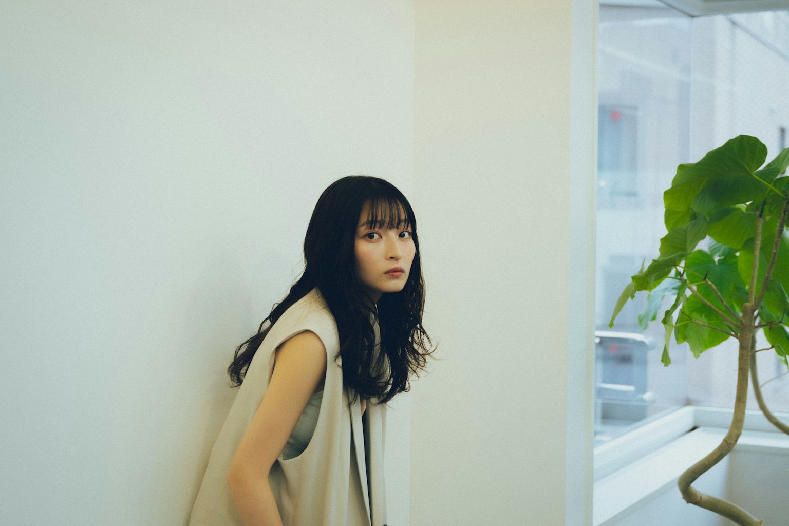 站在白色牆壁前的女人長黑髮和簡單的衣服窗戶透入自然光