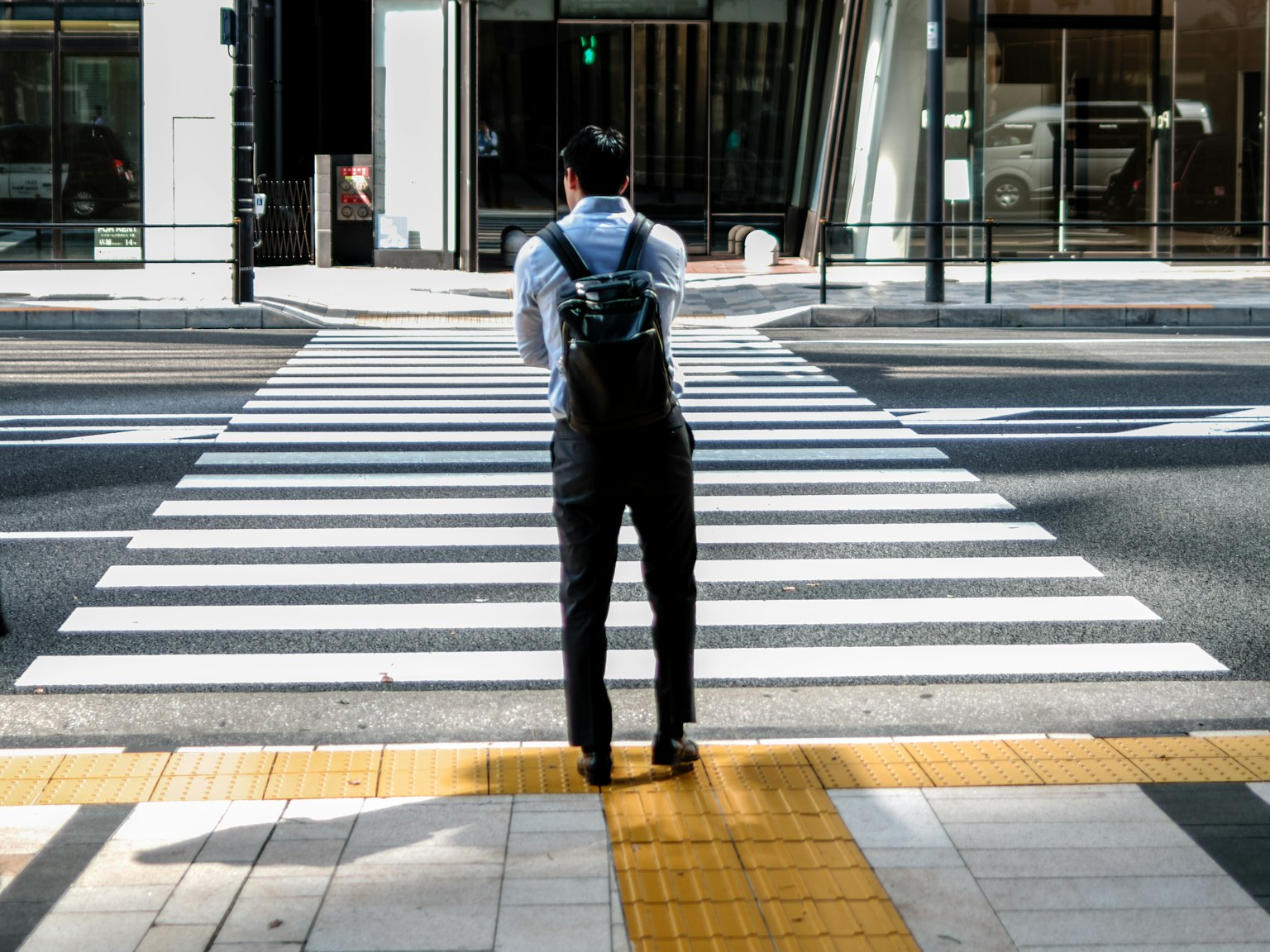 Image d'un homme debout à un passage piéton vu de derrière