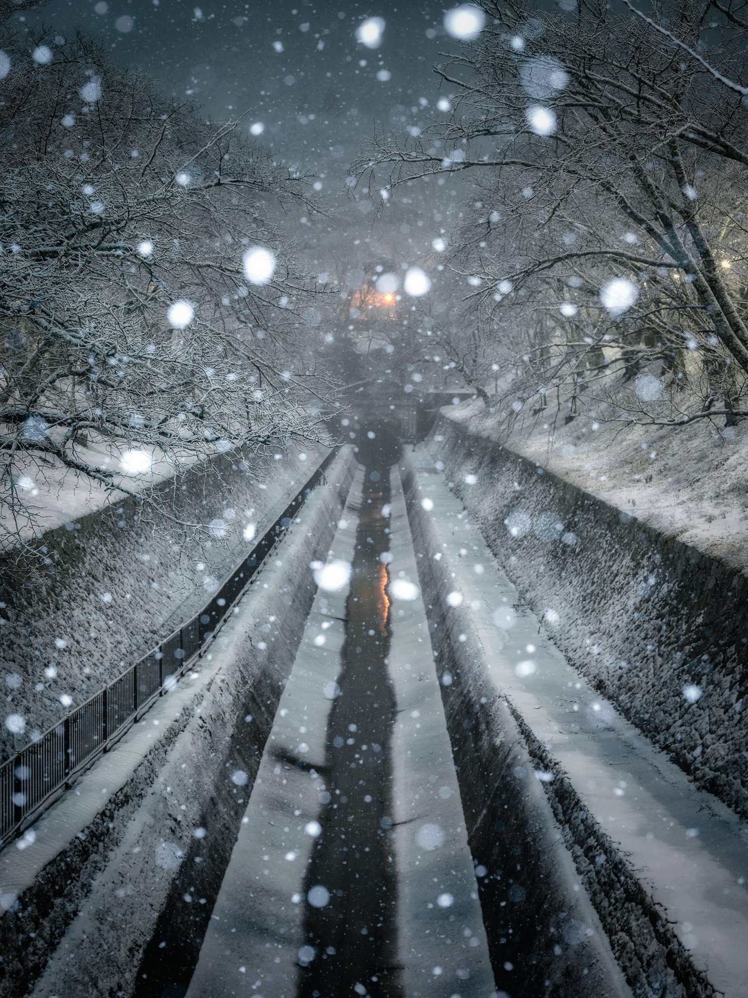 Scène ferroviaire nocturne enneigée avec des ombres et des flocons de neige tombants créant une atmosphère mystique