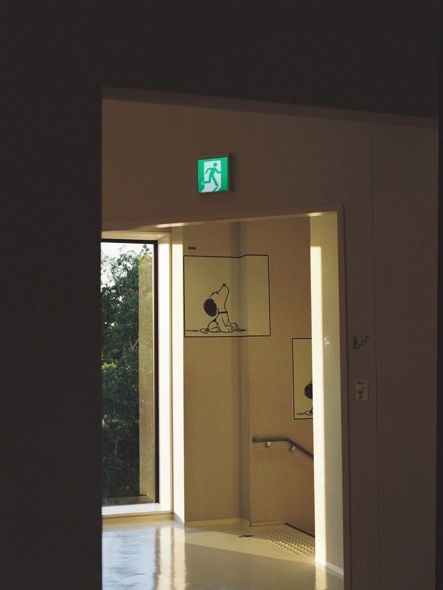 Foto de una puerta con un letrero de salida brillante, vegetación visible afuera