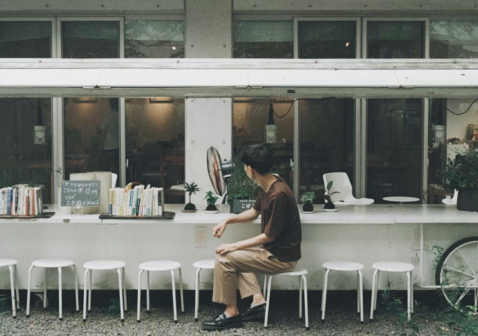 คนที่นั่งอยู่ที่โต๊ะสีขาวในร้านกาแฟที่มีหนังสือรอบๆ