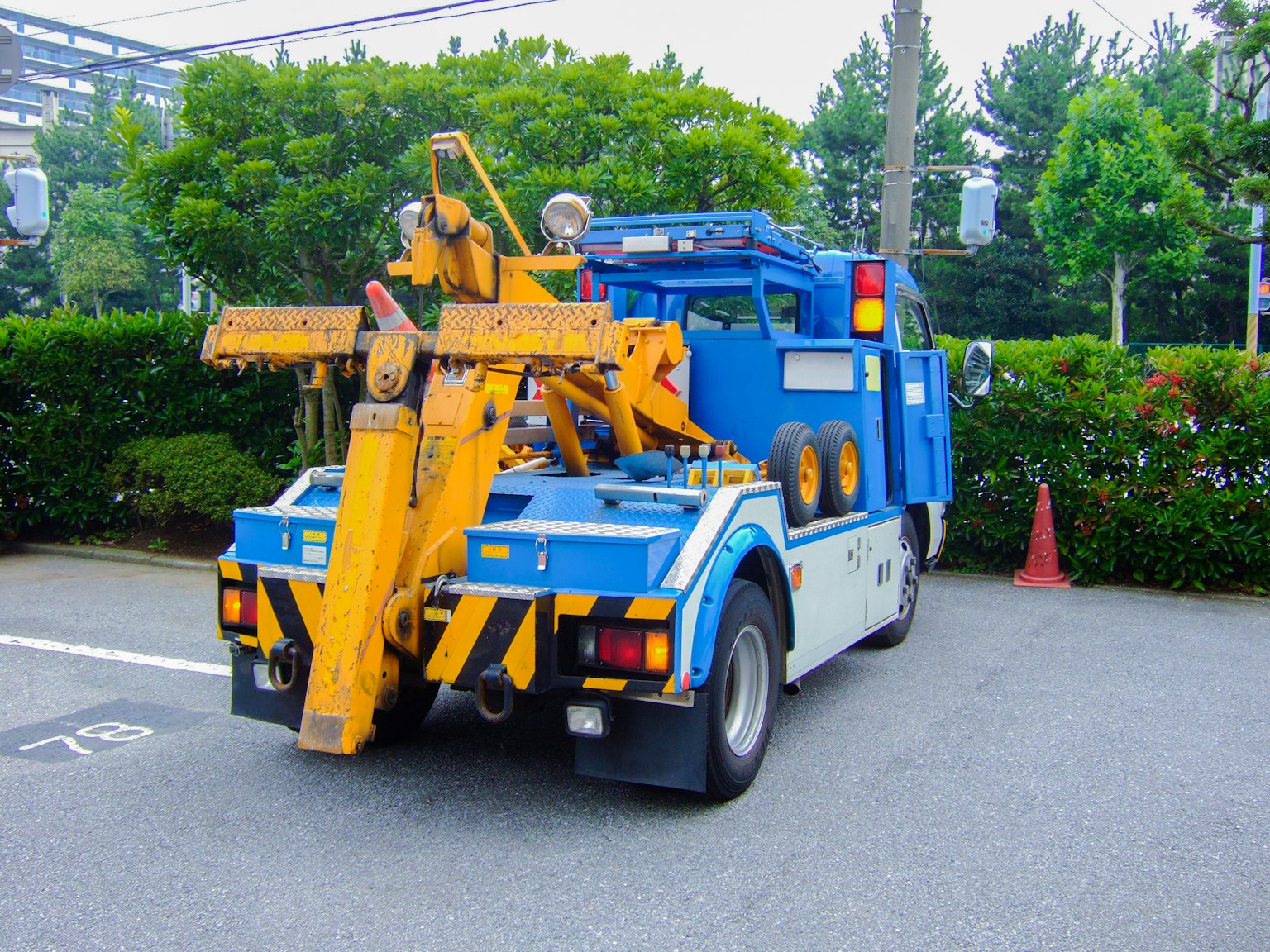 A blue truck with a yellow crane attached parked in a green area